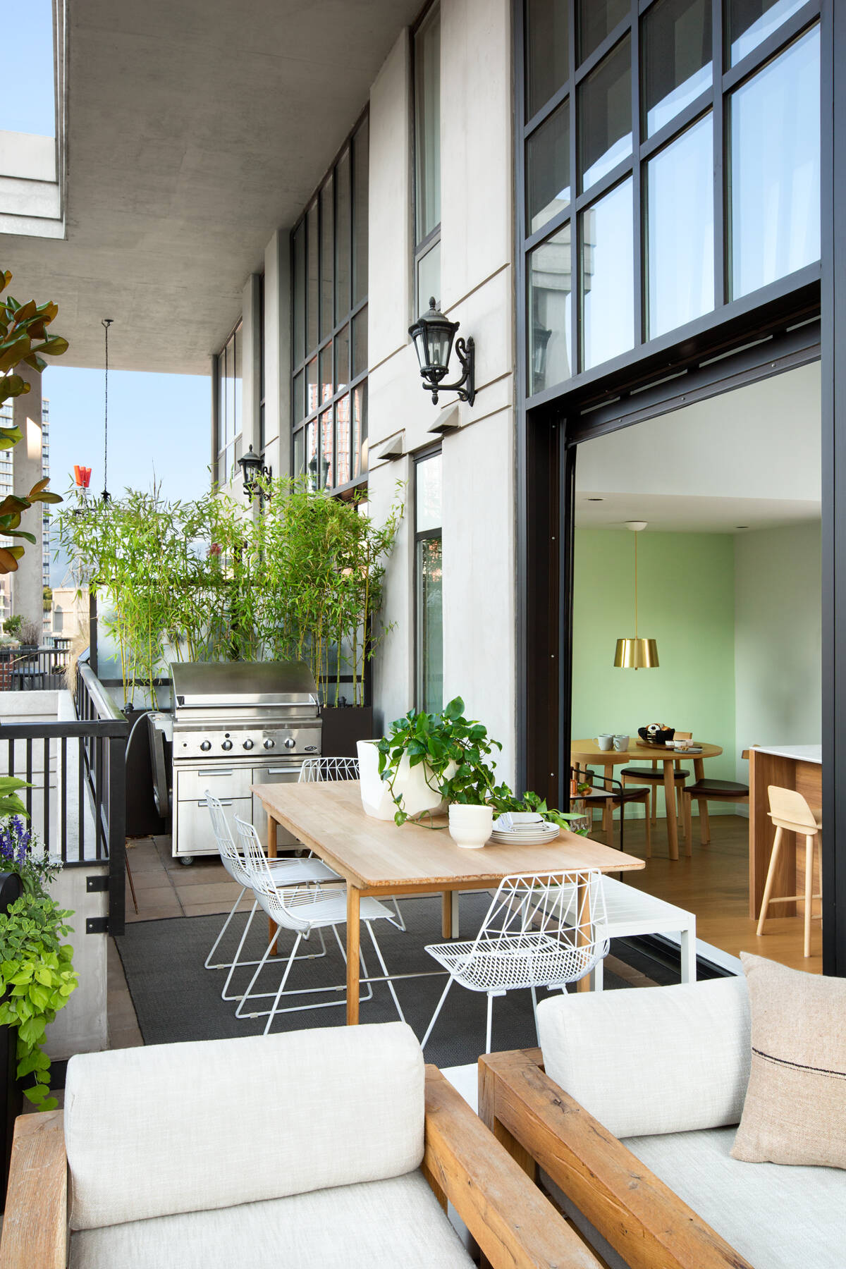 Oversized black-framed windows lift up completely, turning the main living area into an open-air pavilion. Suddenly, the line between indoors and outdoors disappears.
Outside, views of downtown Vancouver set the backdrop for a fully functional living zone. There’s a BBQ and dining area for hosting, plus a fireplace and lounge seating for quiet evenings. It’s a clever use of space in an urban setting, one that adds not just square footage, but quality of life.