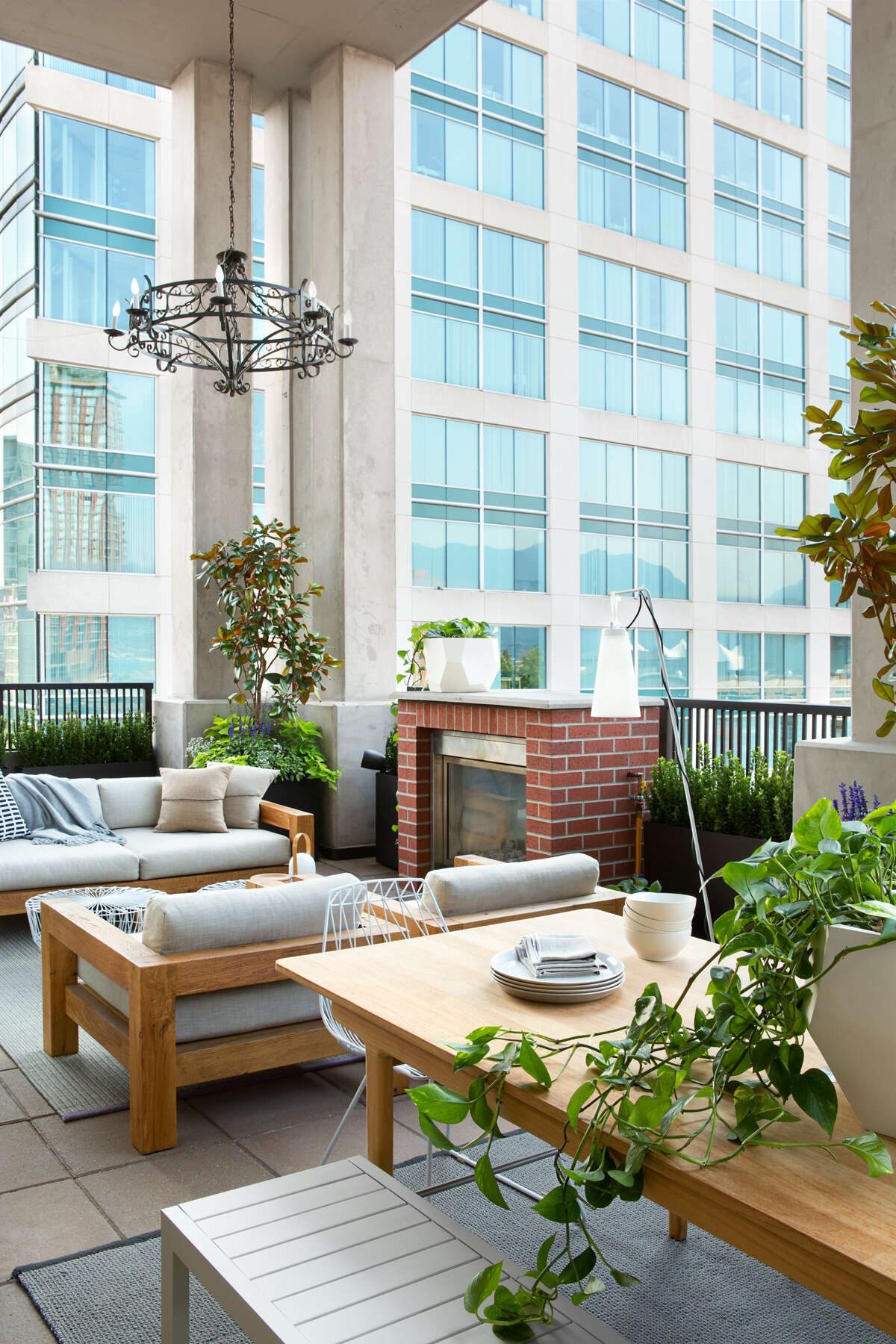 Oversized black-framed windows lift up completely, turning the main living area into an open-air pavilion. Suddenly, the line between indoors and outdoors disappears.
Outside, views of downtown Vancouver set the backdrop for a fully functional living zone. There’s a BBQ and dining area for hosting, plus a fireplace and lounge seating for quiet evenings. It’s a clever use of space in an urban setting, one that adds not just square footage, but quality of life.