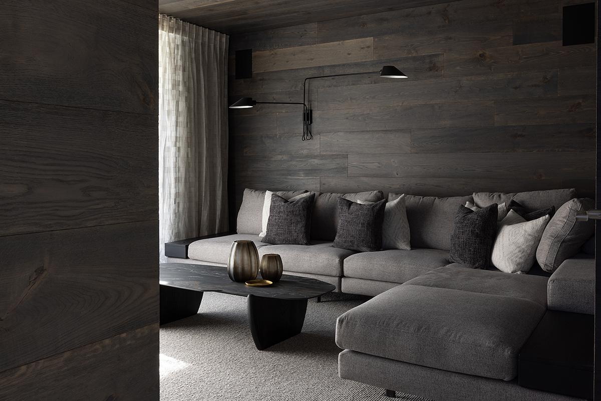 This modern mountain home offers a wood-lined media room designed for comfort and focus. It provides an intimate counterpoint to the openness of the main living zones, giving residents a private space to unwind.