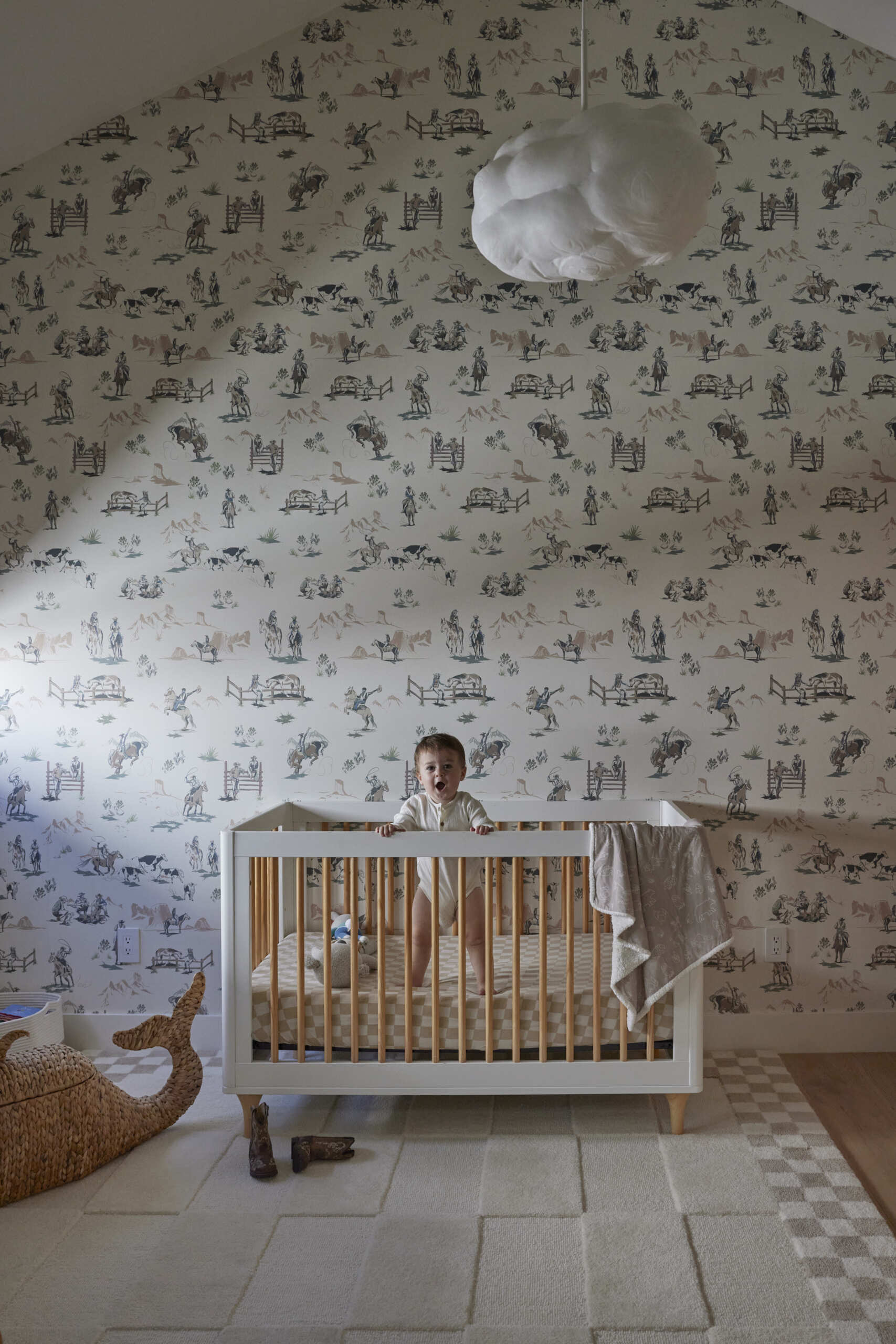 The nursery takes on a vintage cowboy theme with a wallpapered accent wall, creating charm for the youngest family member.