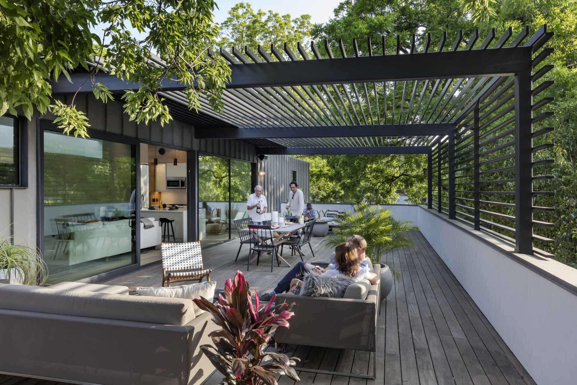 Large custom steel and glass sliding doors open to a roof terrace, extending the living space outdoors. It’s a peaceful spot to relax above the bustle of the garage below, surrounded by treetops and sunlight.