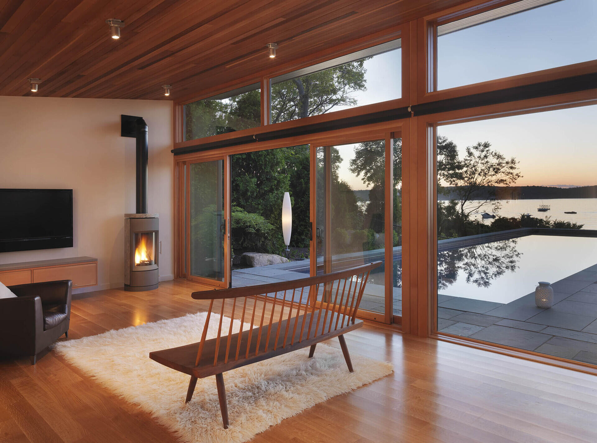 A modern glass-and-wood guest house with a pool and hot tub.
The sloped roof and glass walls frame views of the harbor while inside, yacht-inspired interiors include a custom kitchen, living area, and bath within just 450 square feet.