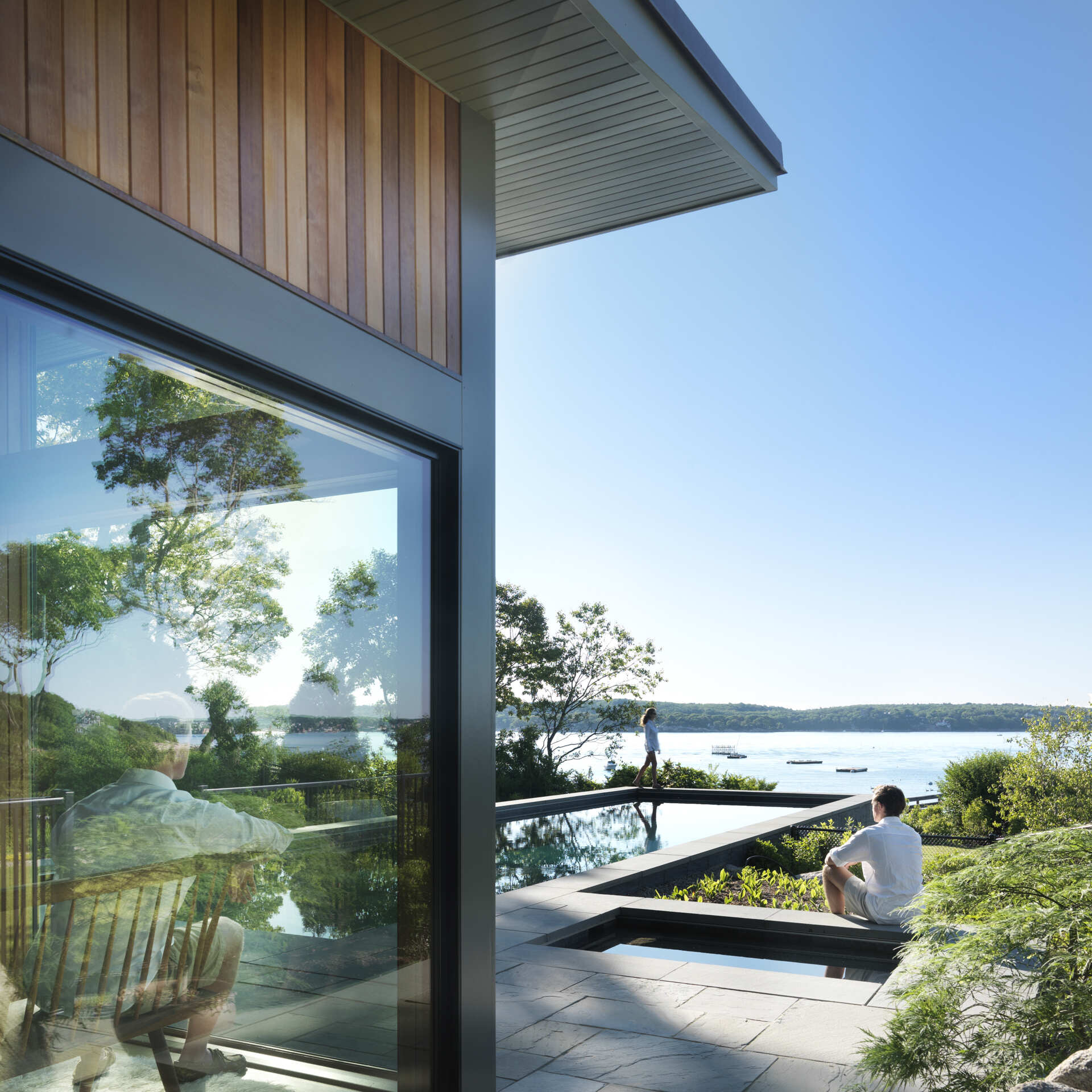 A modern glass-and-wood guest house with a pool and hot tub.
The sloped roof and glass walls frame views of the harbor while inside, yacht-inspired interiors include a custom kitchen, living area, and bath within just 450 square feet.