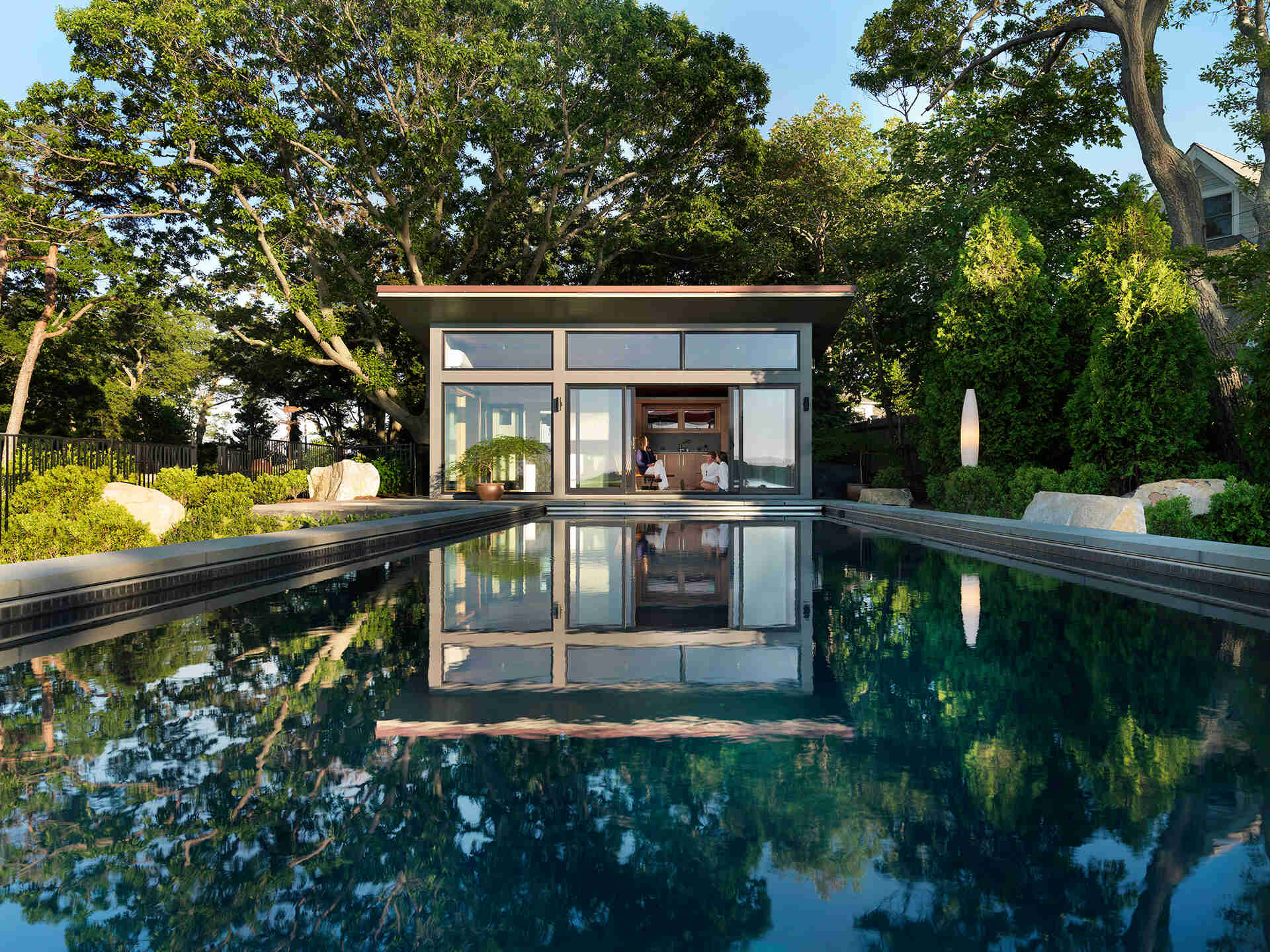A modern glass-and-wood guest house with a pool and hot tub.
The sloped roof and glass walls frame views of the harbor while inside, yacht-inspired interiors include a custom kitchen, living area, and bath within just 450 square feet.