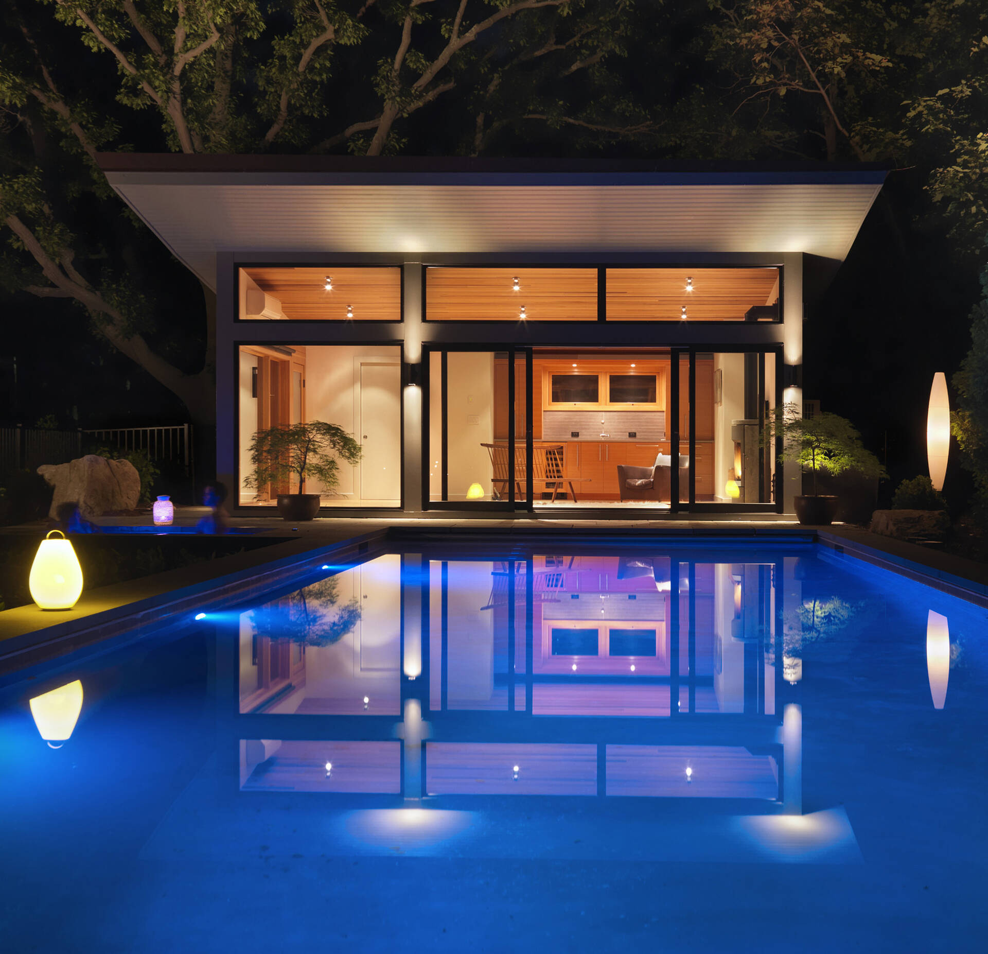 A modern glass-and-wood guest house with a pool and hot tub.
The sloped roof and glass walls frame views of the harbor while inside, yacht-inspired interiors include a custom kitchen, living area, and bath within just 450 square feet.