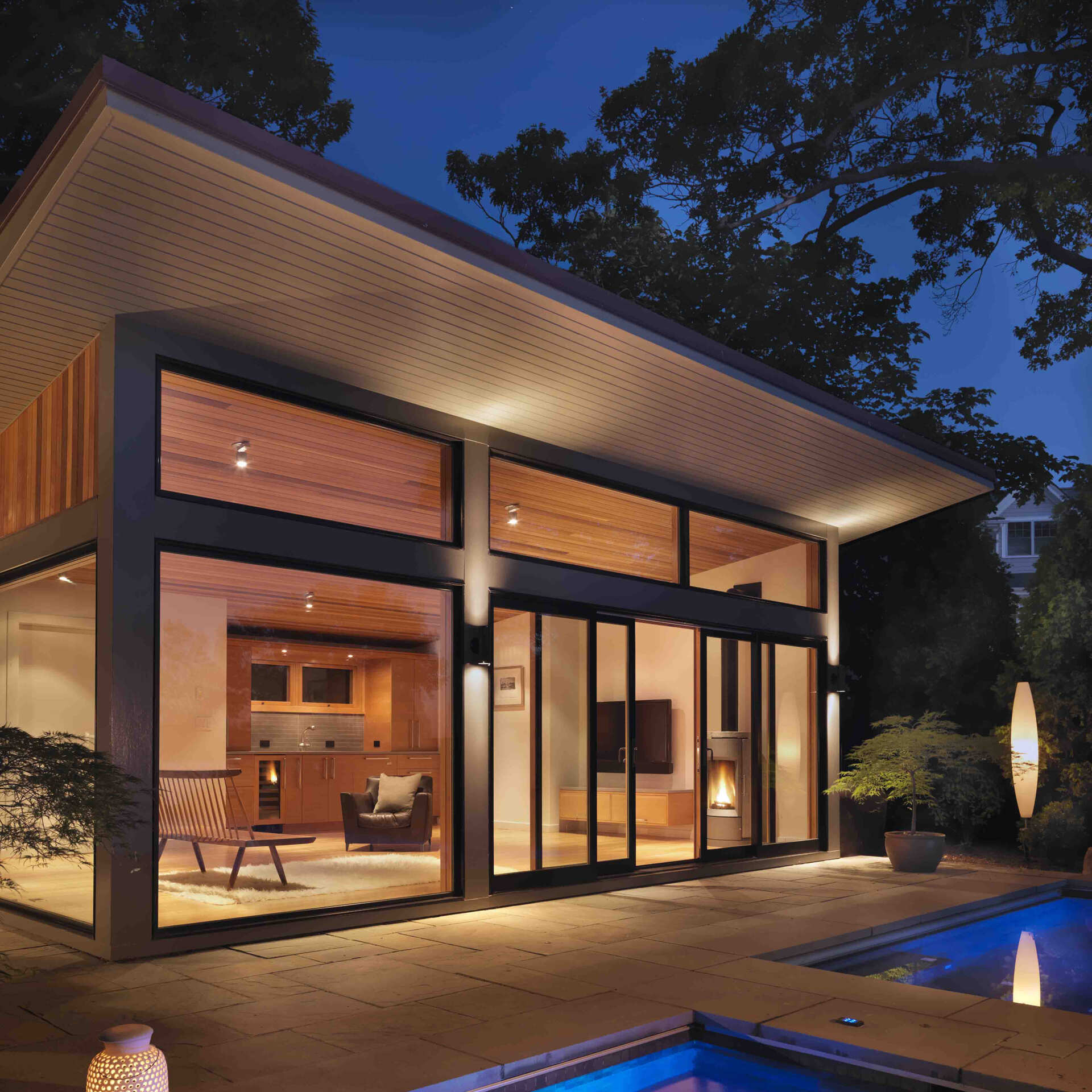 A modern glass-and-wood guest house with a pool and hot tub.
The sloped roof and glass walls frame views of the harbor while inside, yacht-inspired interiors include a custom kitchen, living area, and bath within just 450 square feet.