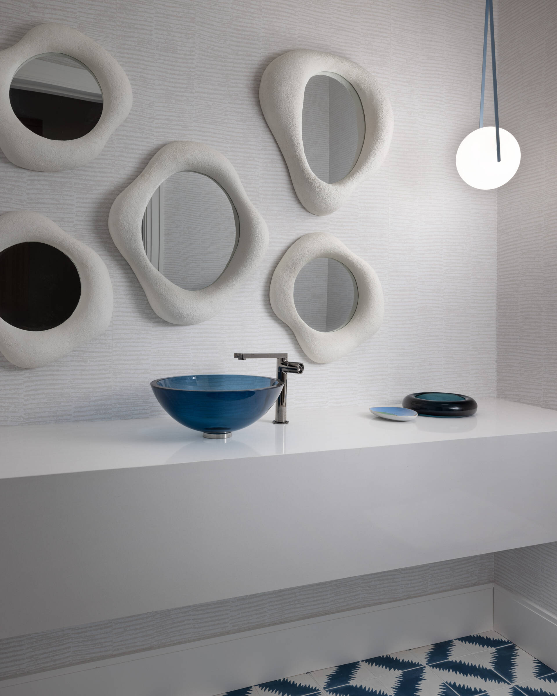Small room, big mood. Sculptural mirrors, a blue basin, and clever lighting turn the powder room into an unexpected moment. Guests will talk.