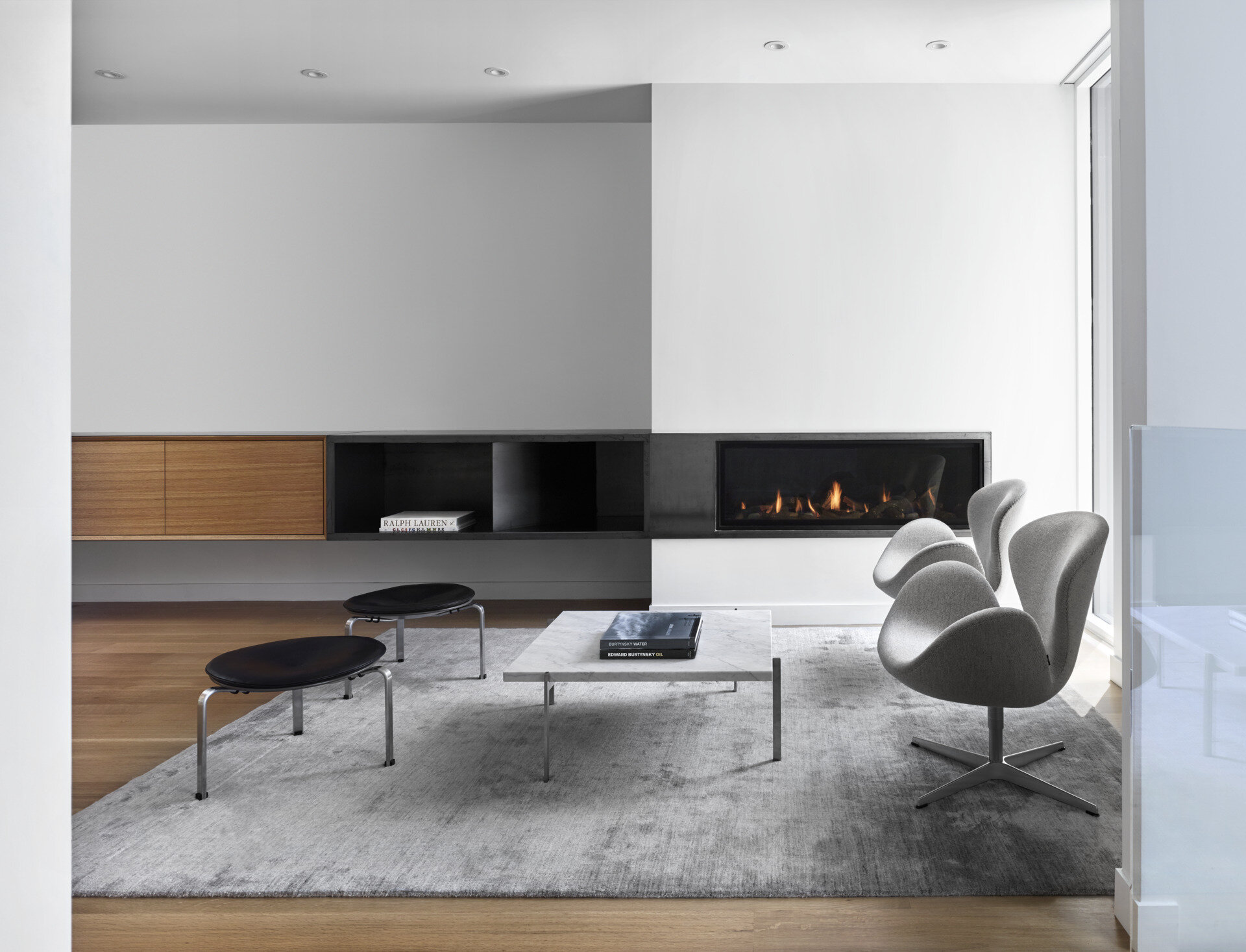 A modern sitting area with a built-in fireplace and street views inside a minimalist Toronto home designed for family living.