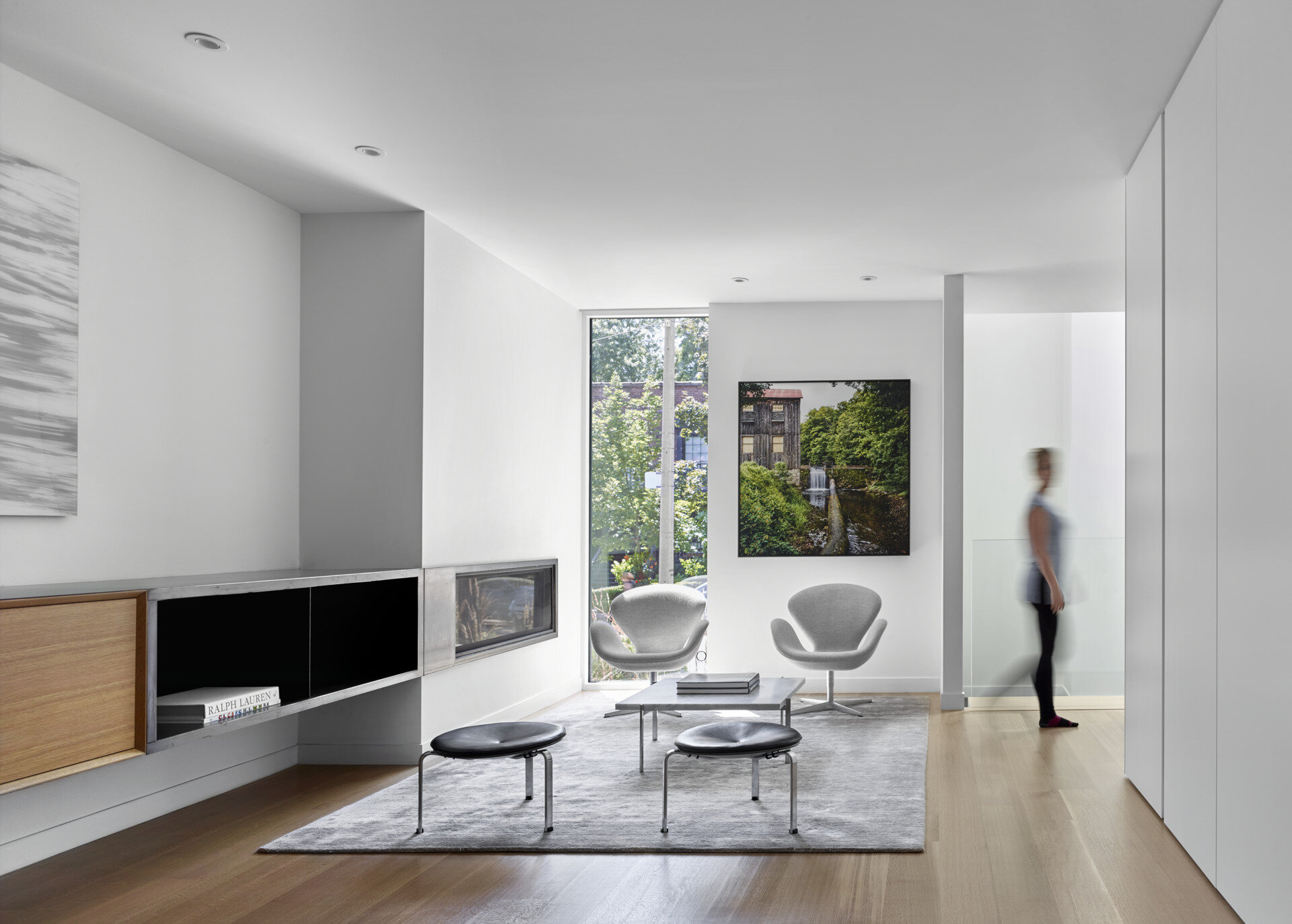 A modern sitting area with a built-in fireplace and street views inside a minimalist Toronto home designed for family living.