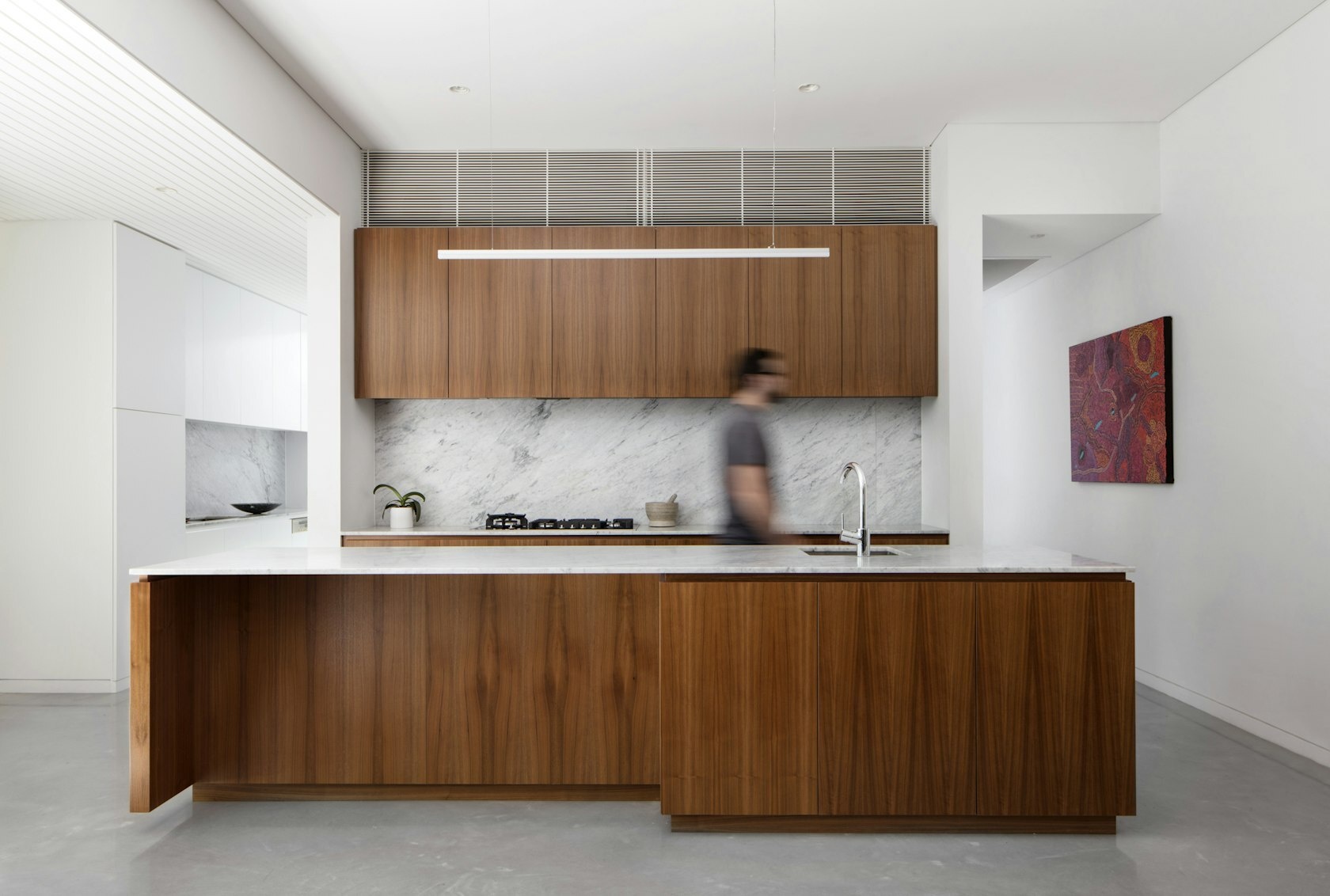 American Walnut cabinetry meets white stone and minimalist lines in this warm, modern kitchen design.