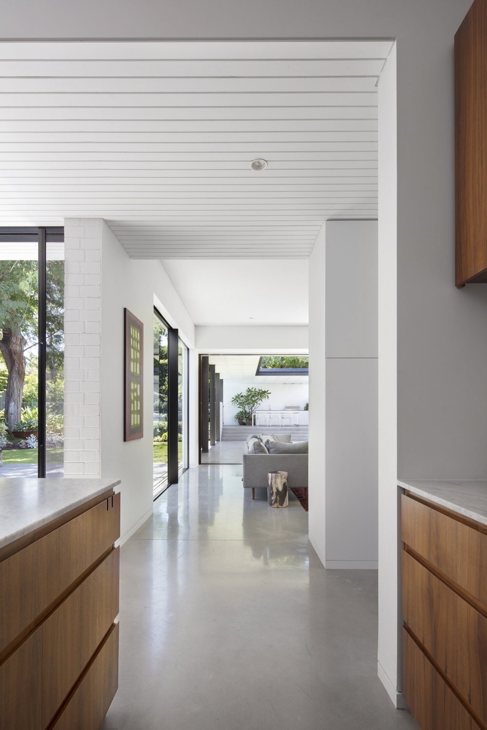 The living room opens entirely to the backyard through concealed sliding glass doors for seamless indoor-outdoor living.