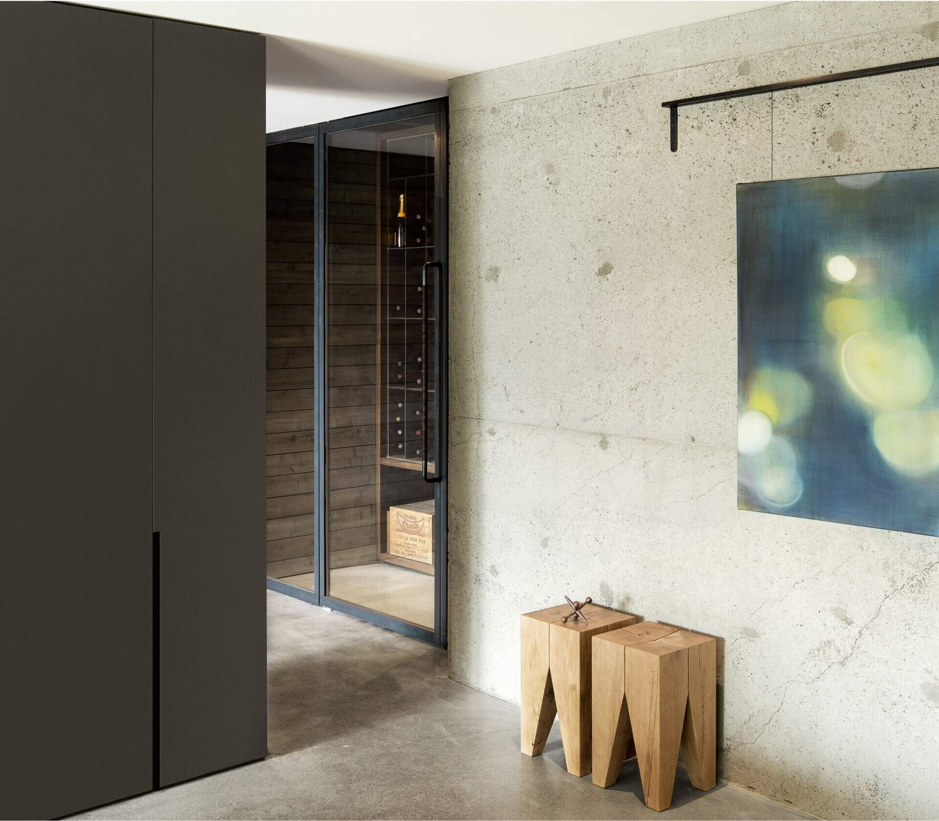An exposed foundation wall leads to a small wine cellar and workshop, adding texture and character to the renovated lower level.