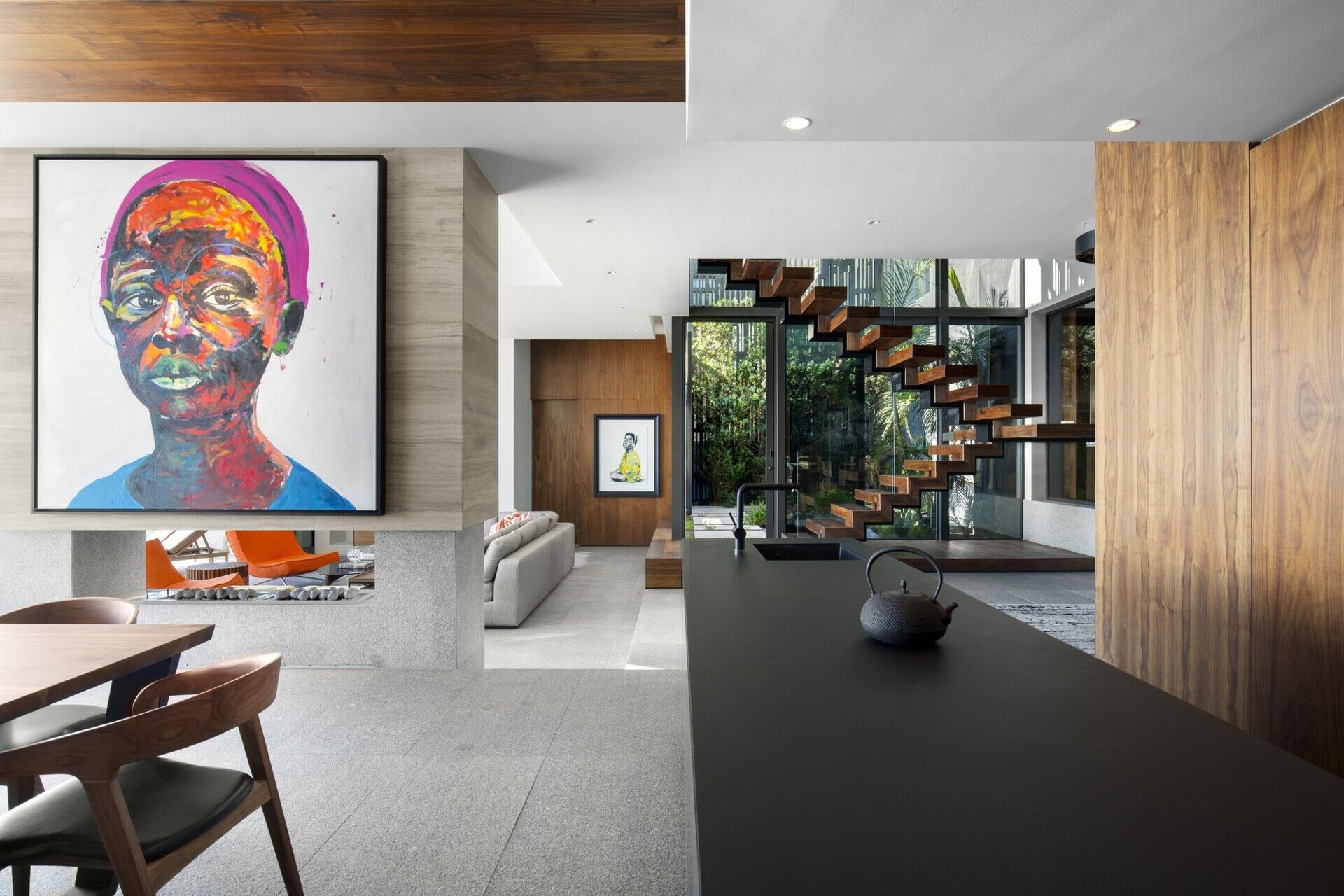 Sleek black-and-wood kitchen with long island and hidden appliances, blending functionality with style.