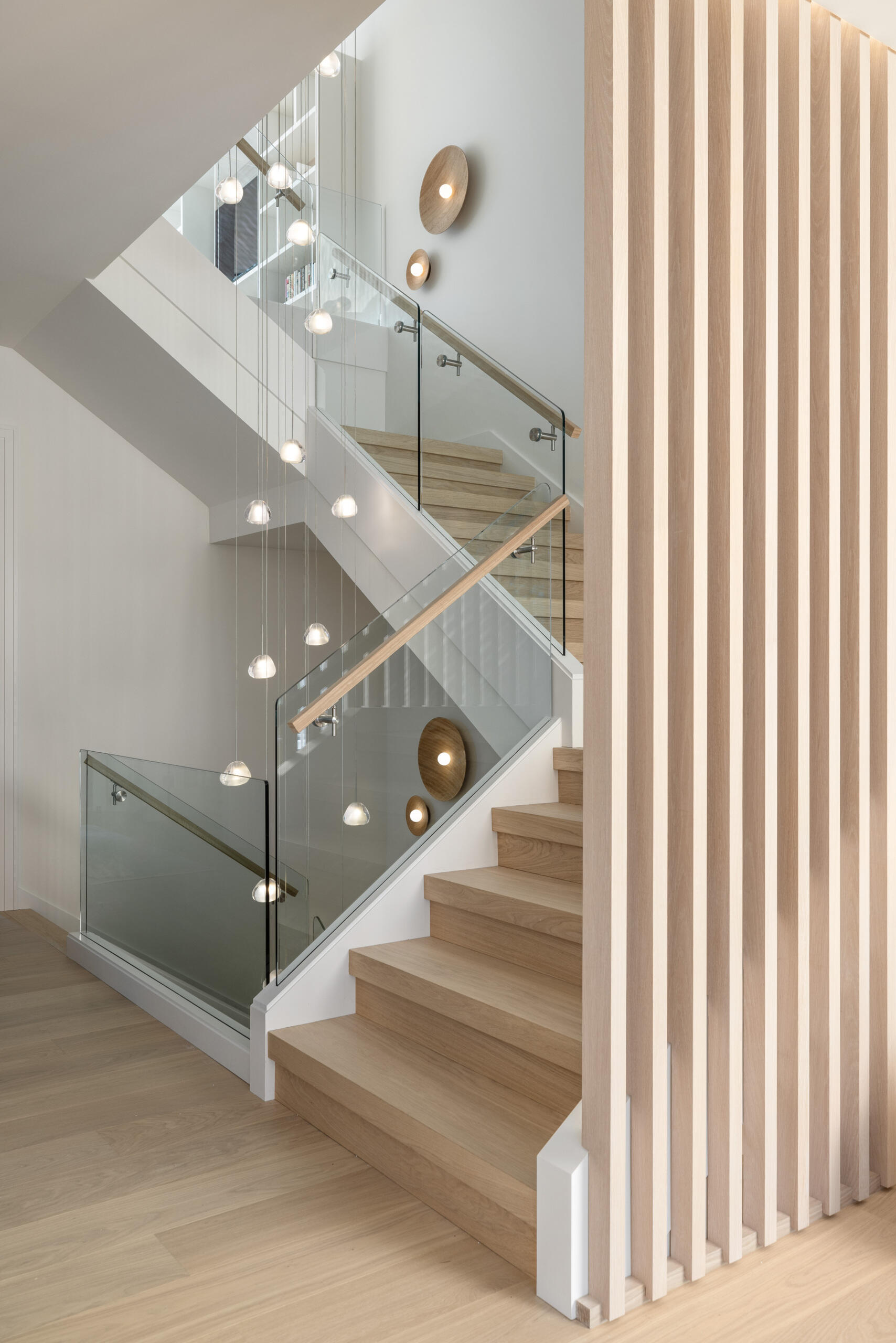 Glass, vertical slats, and floating treads make the staircase a daily sculpture. It filters light across floors and ties the home’s calm geometry together. It is a photograph waiting to happen from every angle.