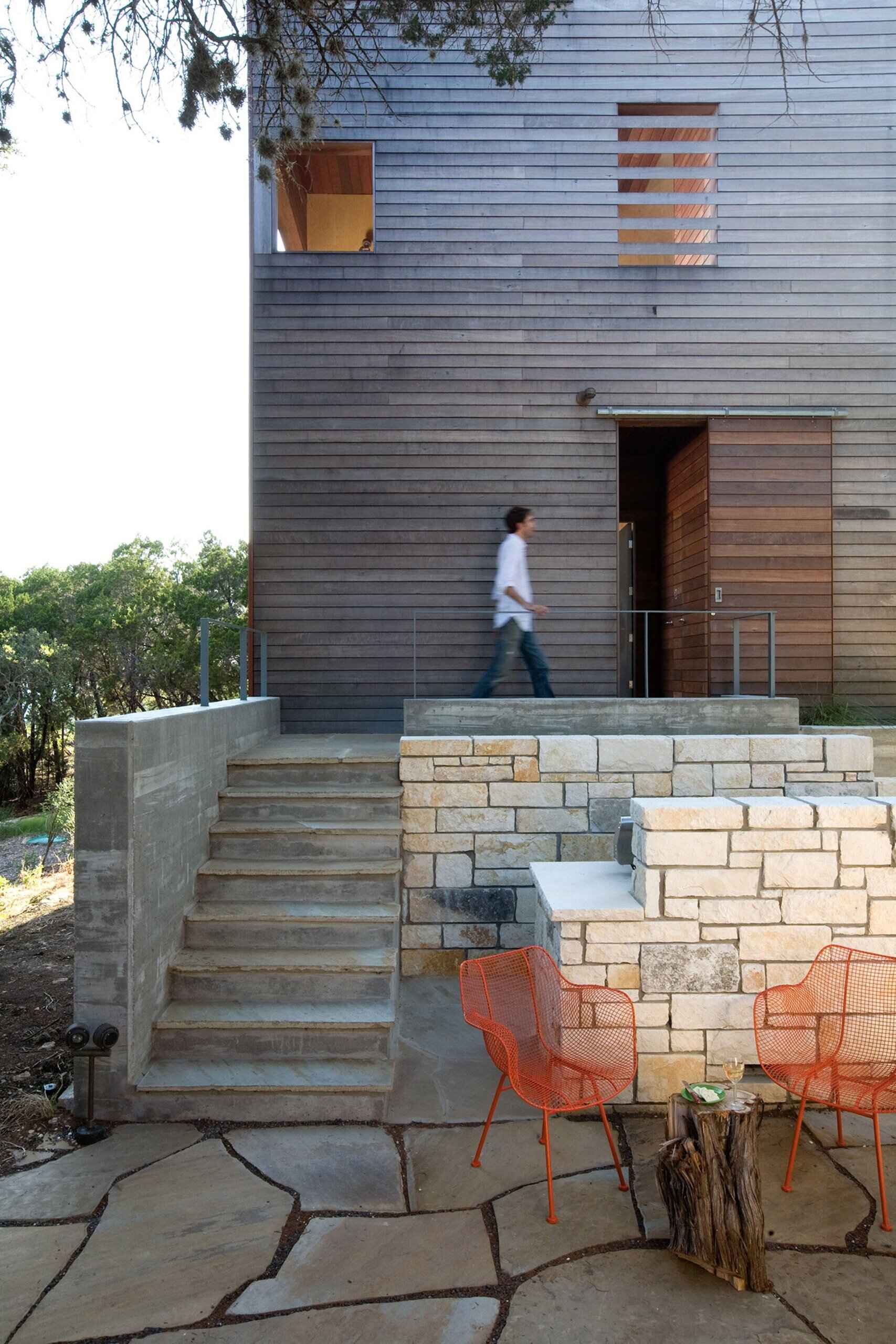 A modern tower built beside a 1930s cabin in Austin, Texas, blending old stone and new wood in a serene forest retreat.