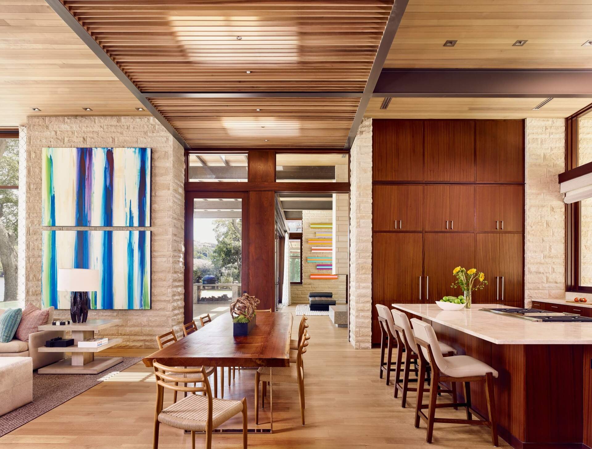 The kitchen’s warm wood cabinetry and light countertops complement the limestone palette, flowing seamlessly into the dining space.