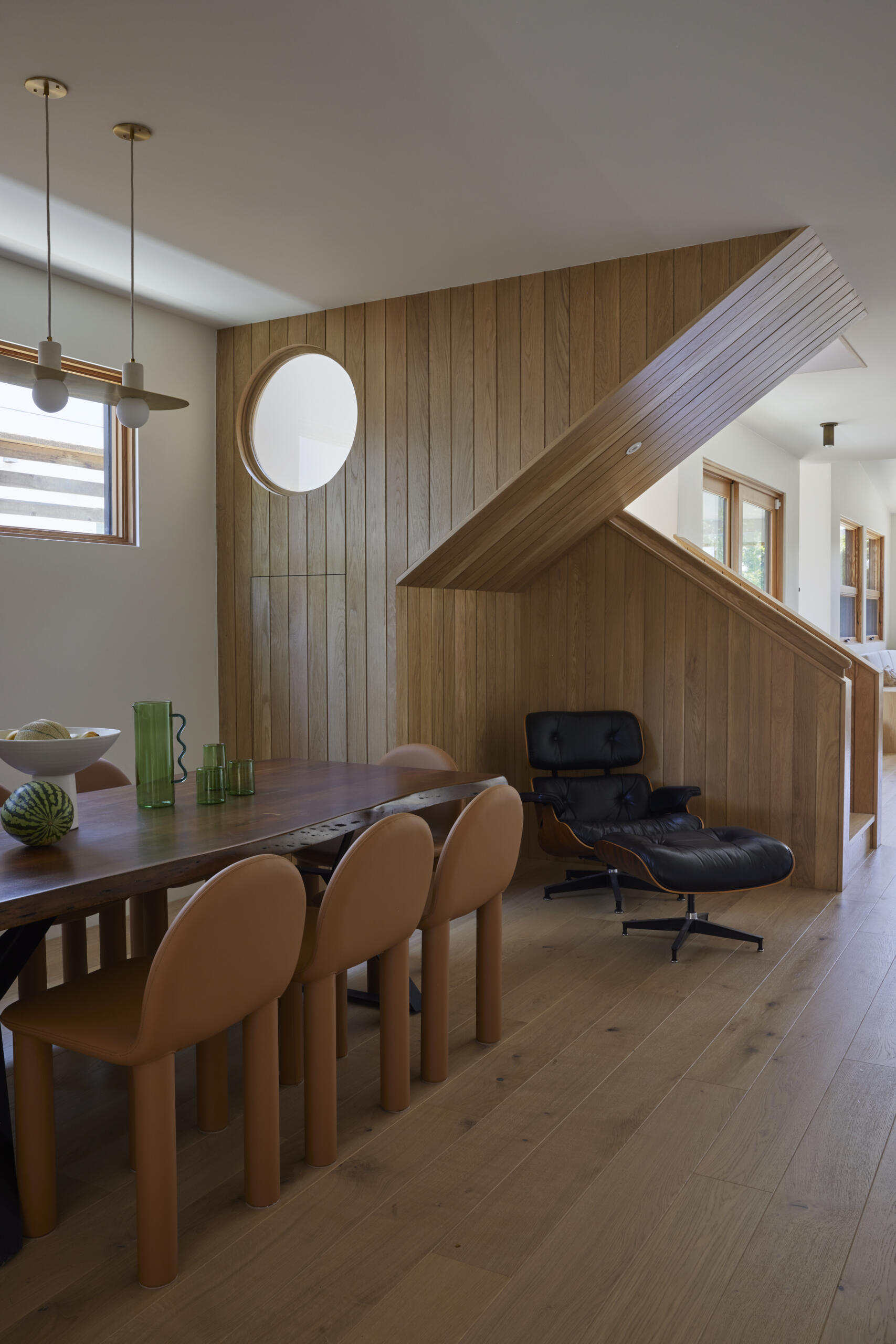 The sculptural white oak staircase doubles as art, featuring a playful round peek-a-boo cutout that adds a lighthearted touch.