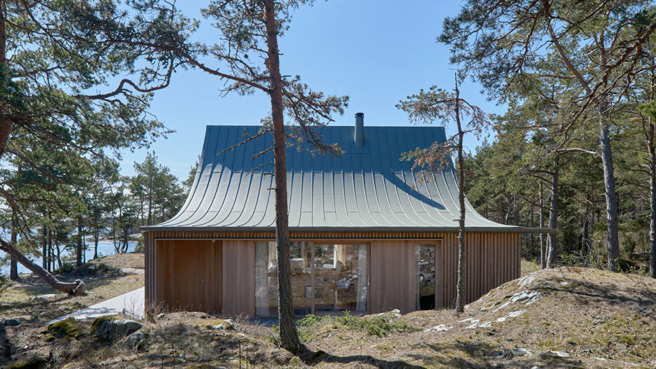 A sculptural cedar house by Tham & Videgård Arkitekter rises like a tent from the rocks of Krokholmen island, combining modern design with the simplicity of Swedish summer living.