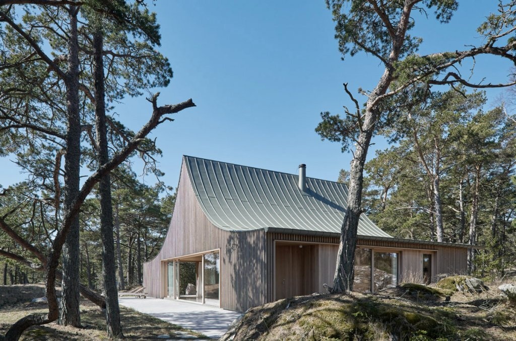 A sculptural cedar house by Tham & Videgård Arkitekter rises like a tent from the rocks of Krokholmen island, combining modern design with the simplicity of Swedish summer living.