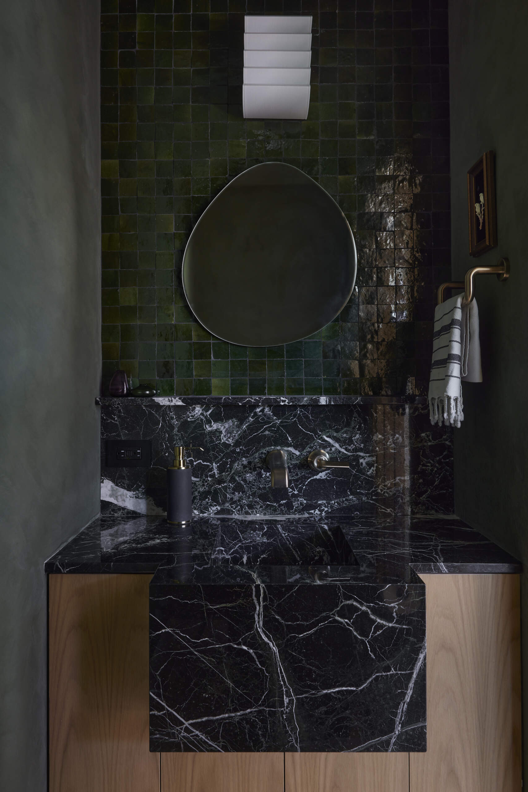 Moody and sculptural, the powder room features limewash walls and a cantilevered integrated stone sink that feels like a piece of art.