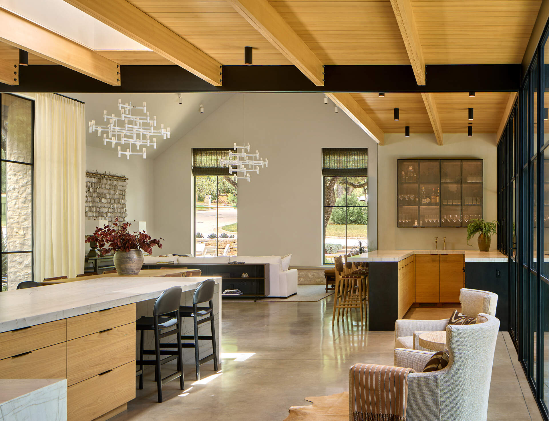Tucked neatly into the open-plan space, the bar area blends elegance with function. A wall-mounted glass-front cabinet displays glassware with precision, turning storage into a design feature. Below, a streamlined counter with dual faucets creates a flexible workspace for mixing drinks or serving guests.