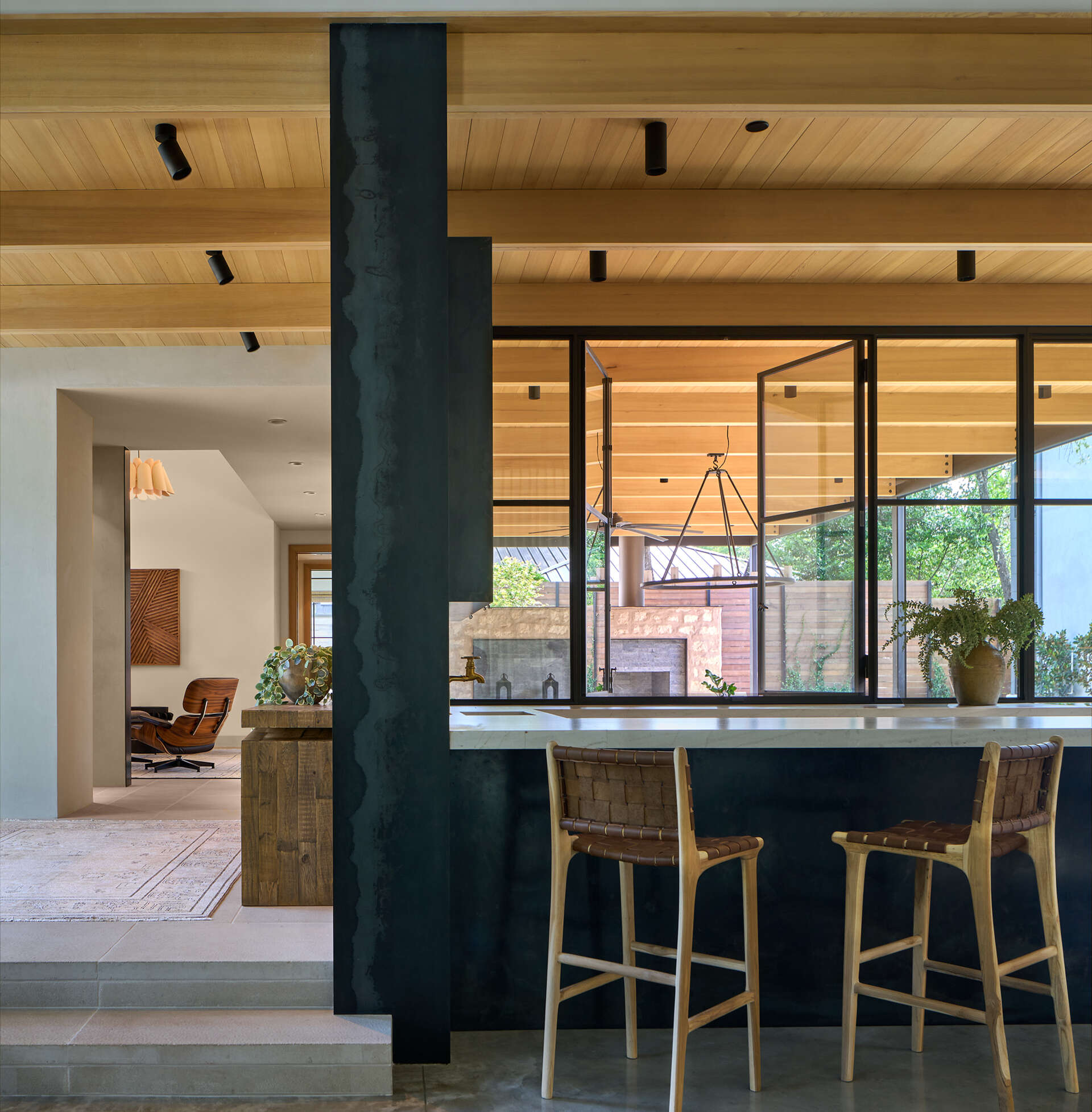 Tucked neatly into the open-plan space, the bar area blends elegance with function. A wall-mounted glass-front cabinet displays glassware with precision, turning storage into a design feature. Below, a streamlined counter with dual faucets creates a flexible workspace for mixing drinks or serving guests.