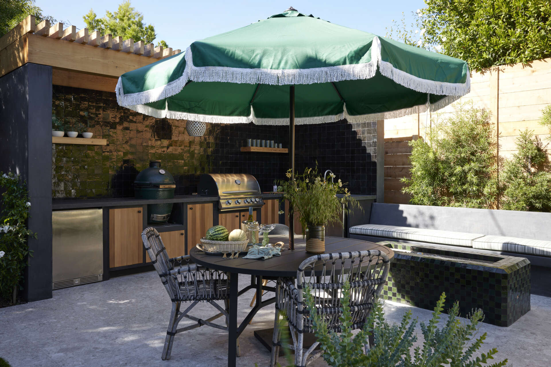 A full outdoor kitchen and tiled fire table extend living outdoors, creating a multifunctional space for cooking, entertaining, and gathering year-round.