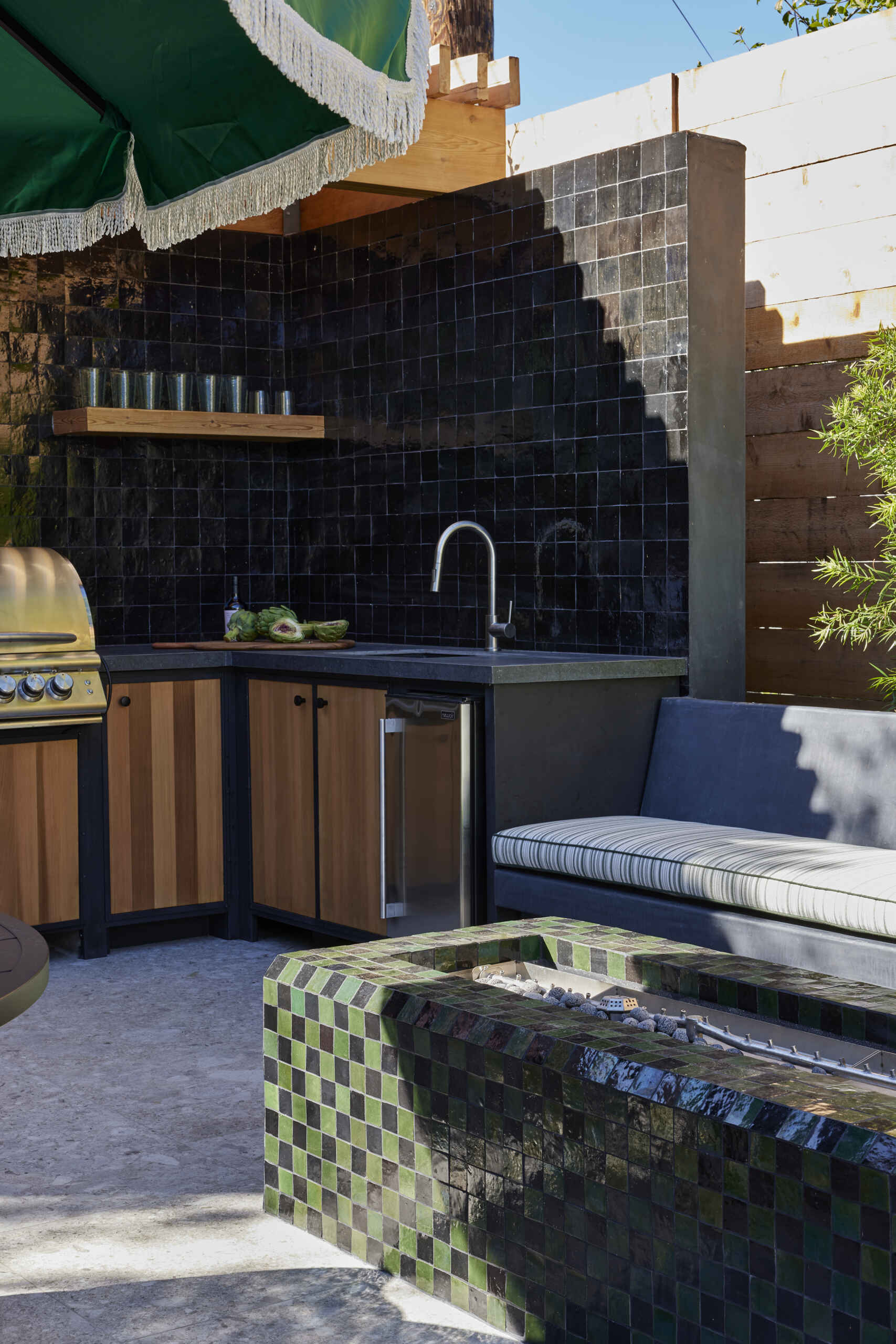 A full outdoor kitchen and tiled fire table extend living outdoors, creating a multifunctional space for cooking, entertaining, and gathering year-round.