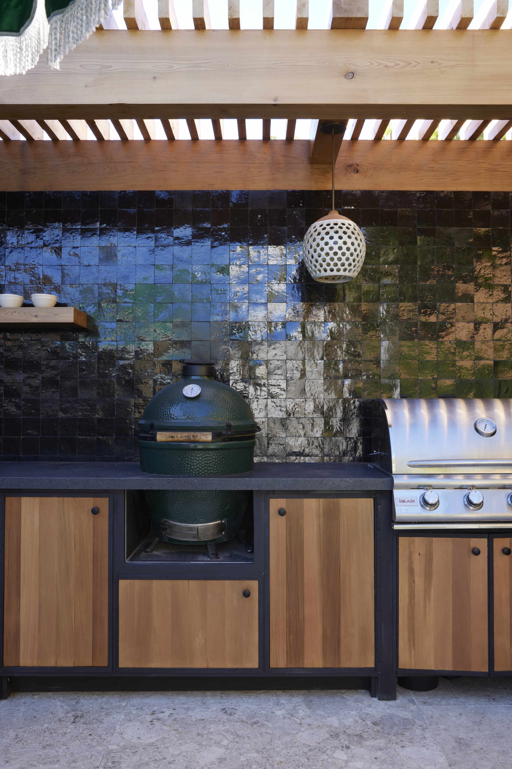 A full outdoor kitchen and tiled fire table extend living outdoors, creating a multifunctional space for cooking, entertaining, and gathering year-round.