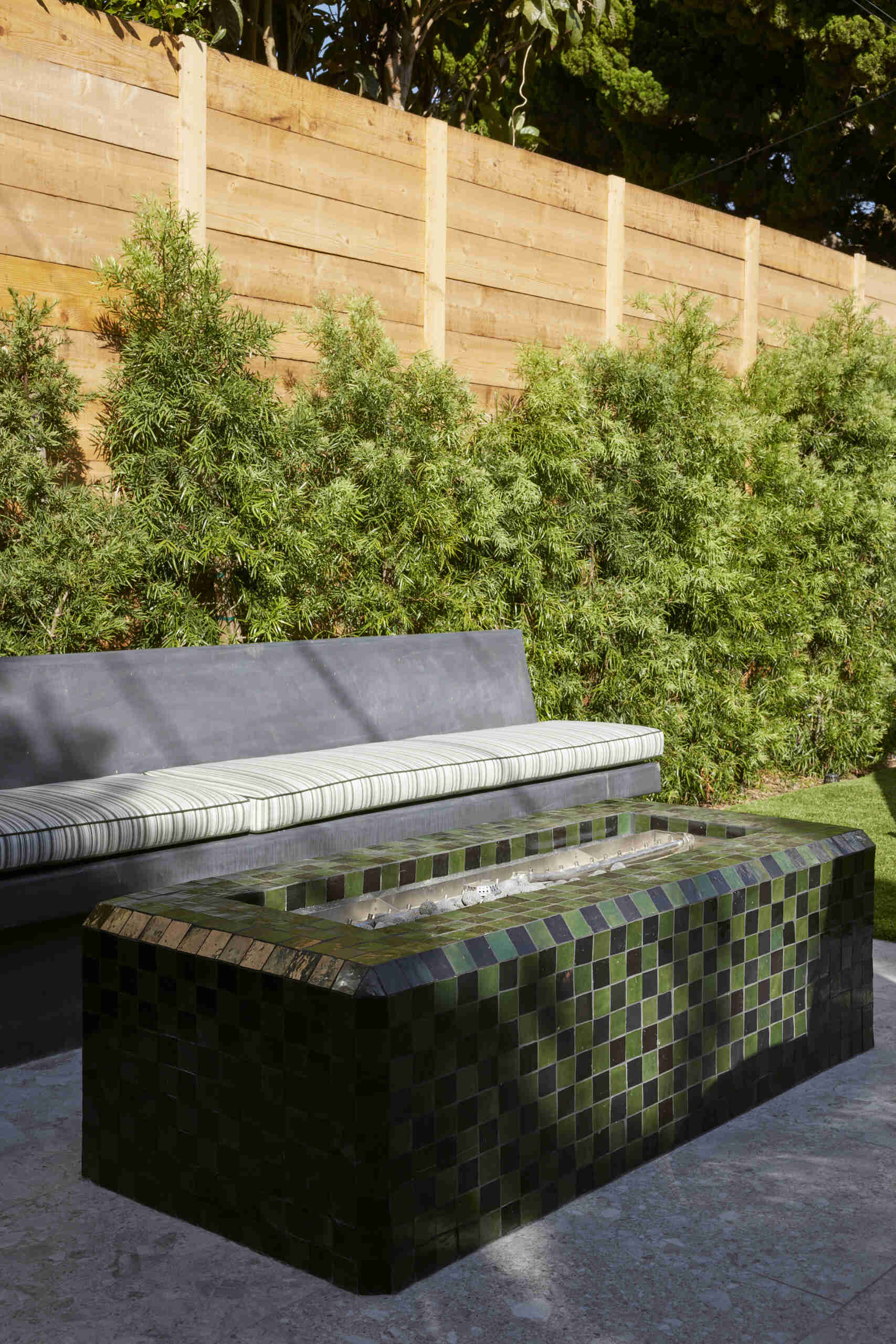 A full outdoor kitchen and tiled fire table extend living outdoors, creating a multifunctional space for cooking, entertaining, and gathering year-round.