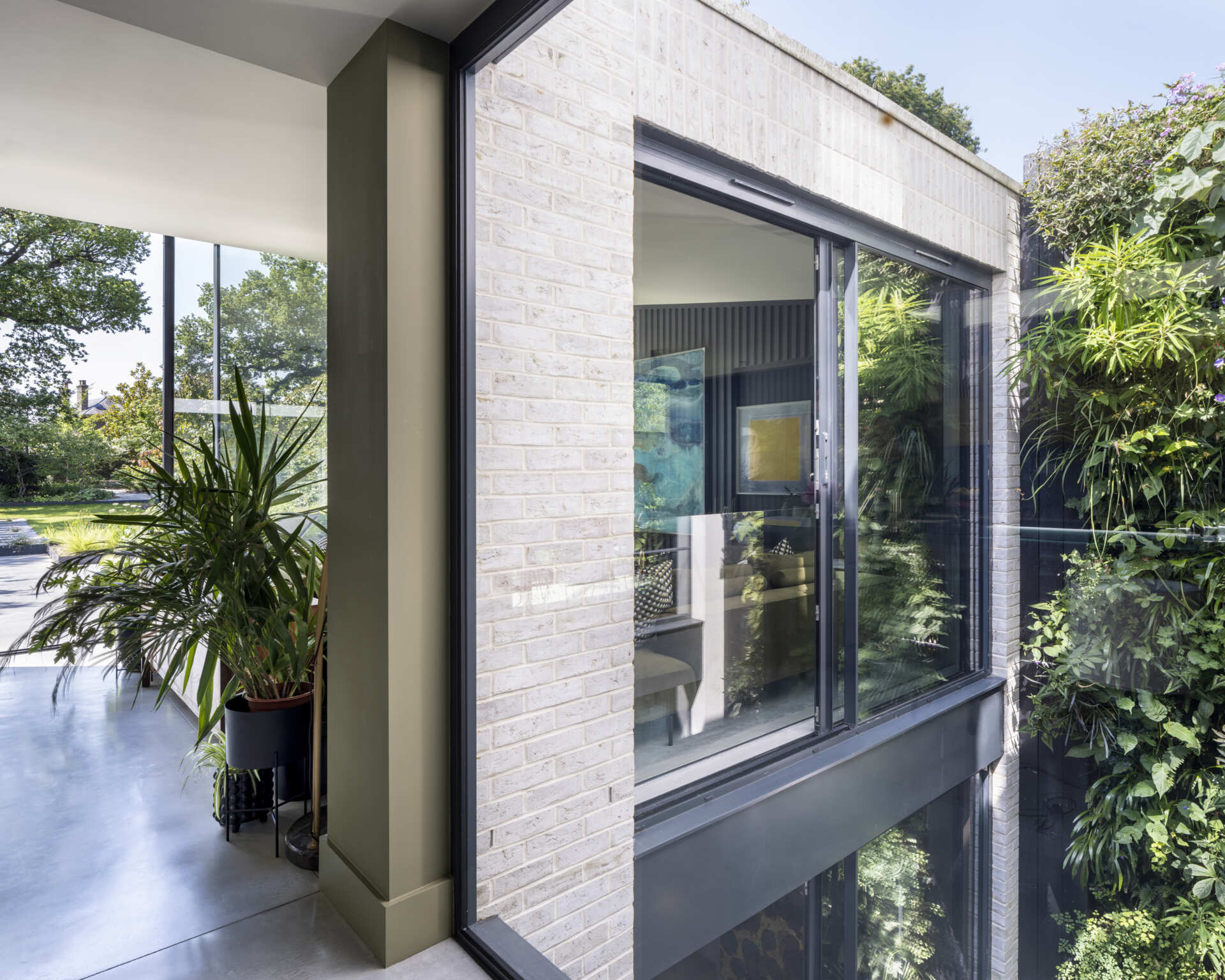 A stunning living wall fills the courtyard with greenery, viewed through a double-height picture window that invites nature inside.