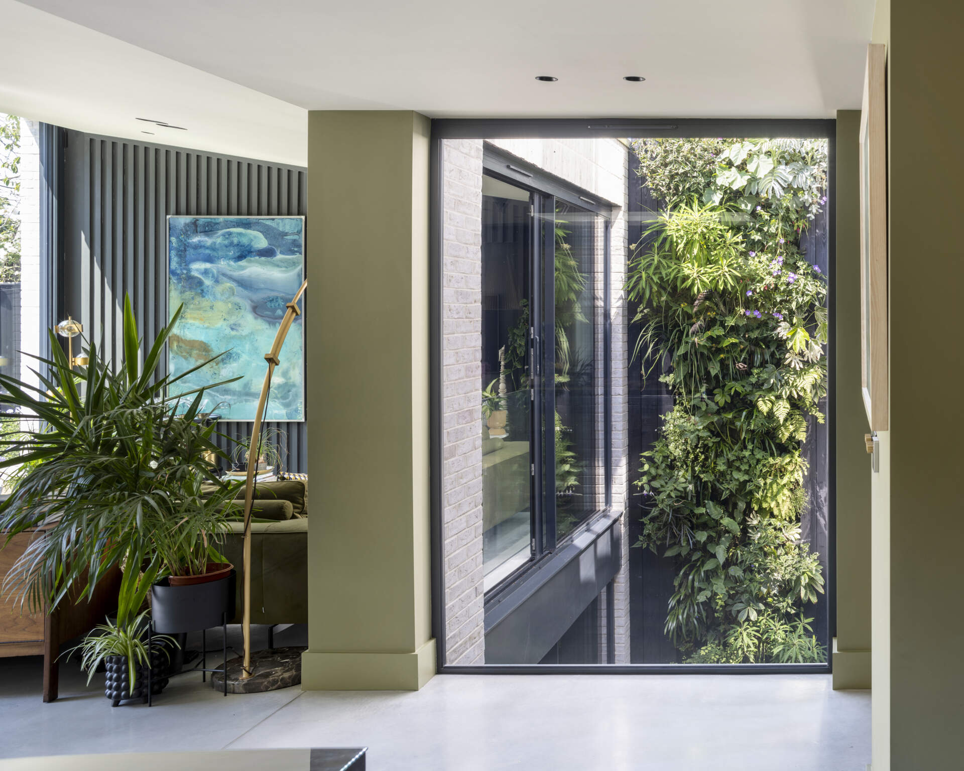 A stunning living wall fills the courtyard with greenery, viewed through a double-height picture window that invites nature inside.