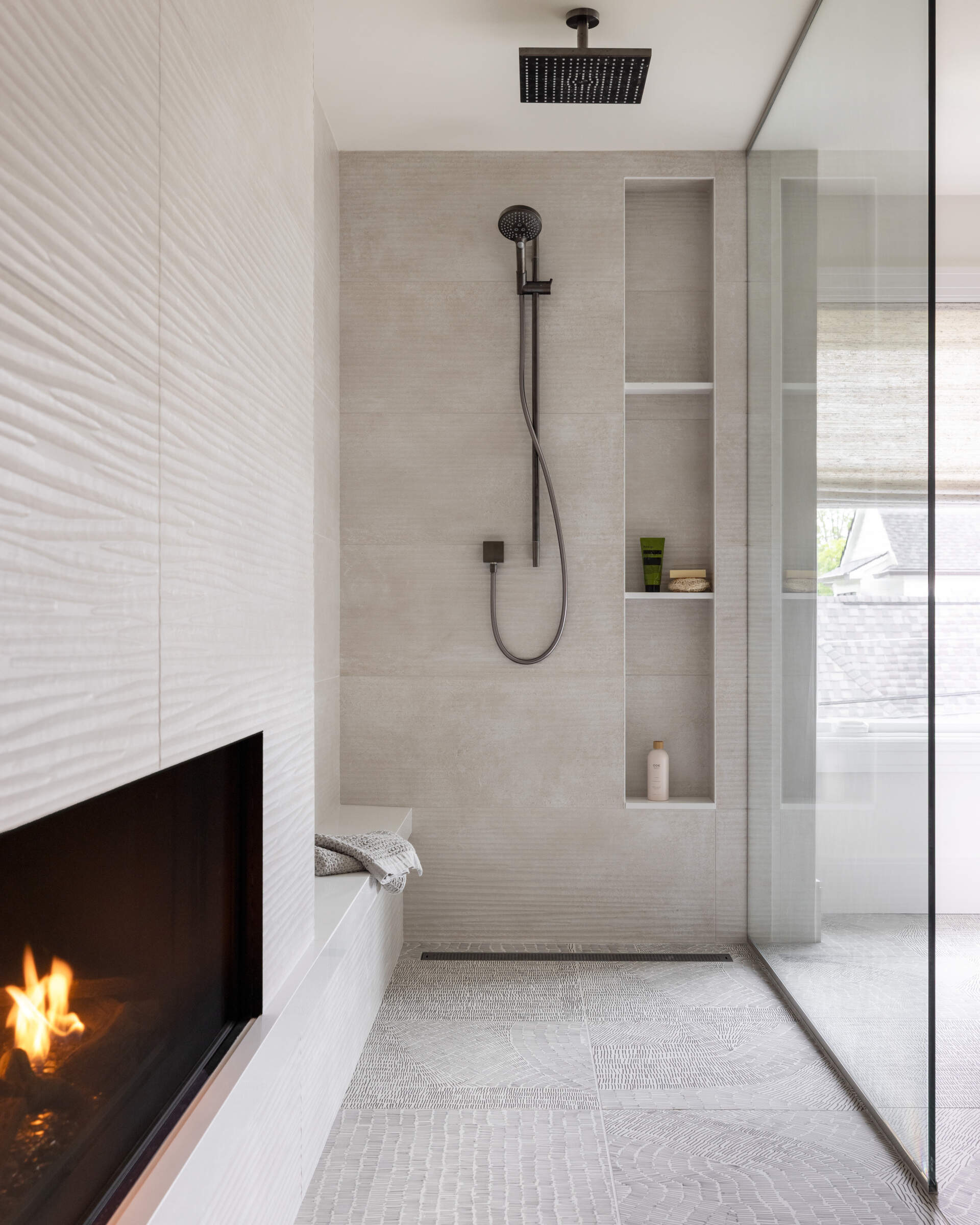 The primary bathroom suite is the headline act. An open layout centers on a double-sided fireplace that stretches from the shower through to the adjoining bedroom. Slide the sleek door closed for privacy or leave it open and let the flames link the two spaces. Morning routine or evening soak, the mood is pure cocoon.
Fixtures earn their place. A Celestica soaking tub sits like a quiet sculpture. Hansgrohe faucets and accessories add precision without fuss. Cabinetry by Scavolini, crafted from Eco Wood, brings a sustainable edge. The materials feel modern, but they are also mindful, which suits the home’s calm brief.
