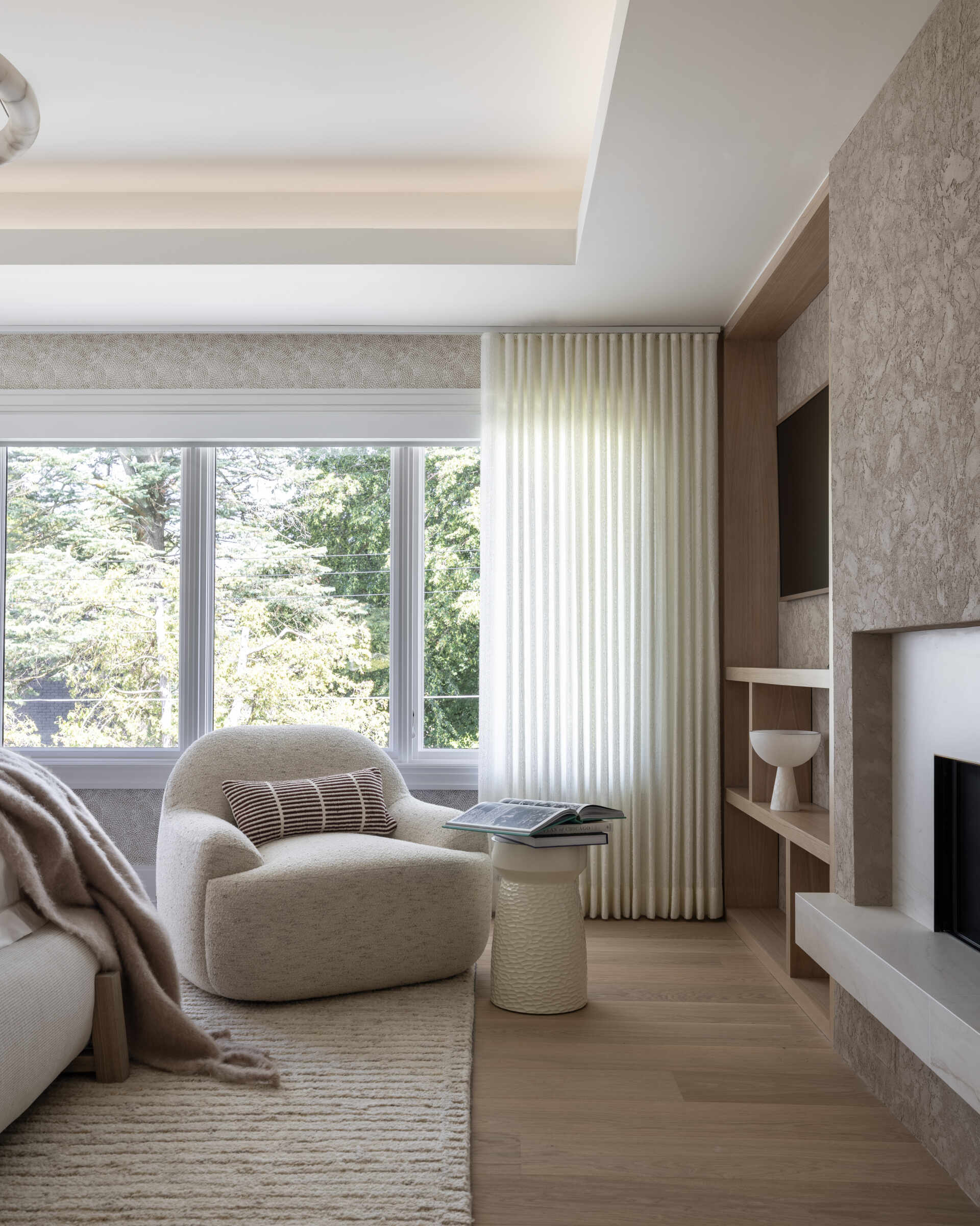 The primary bedroom keeps the palette hushed. Rounded edges, warm lamps, and upholstered textures dial up the comfort. It is generous without feeling grand. The real showpiece waits just beyond.