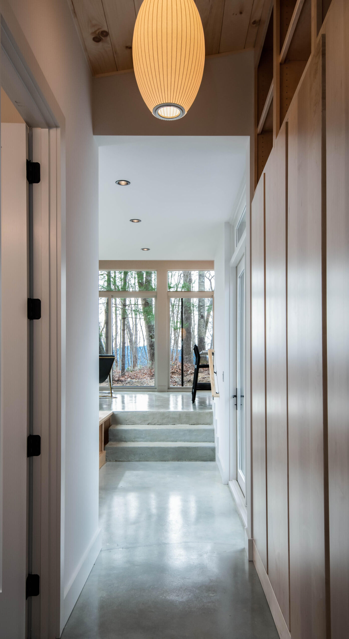 Streamlined hallway with polished concrete floors connecting communal and private areas in a mountain cabin.