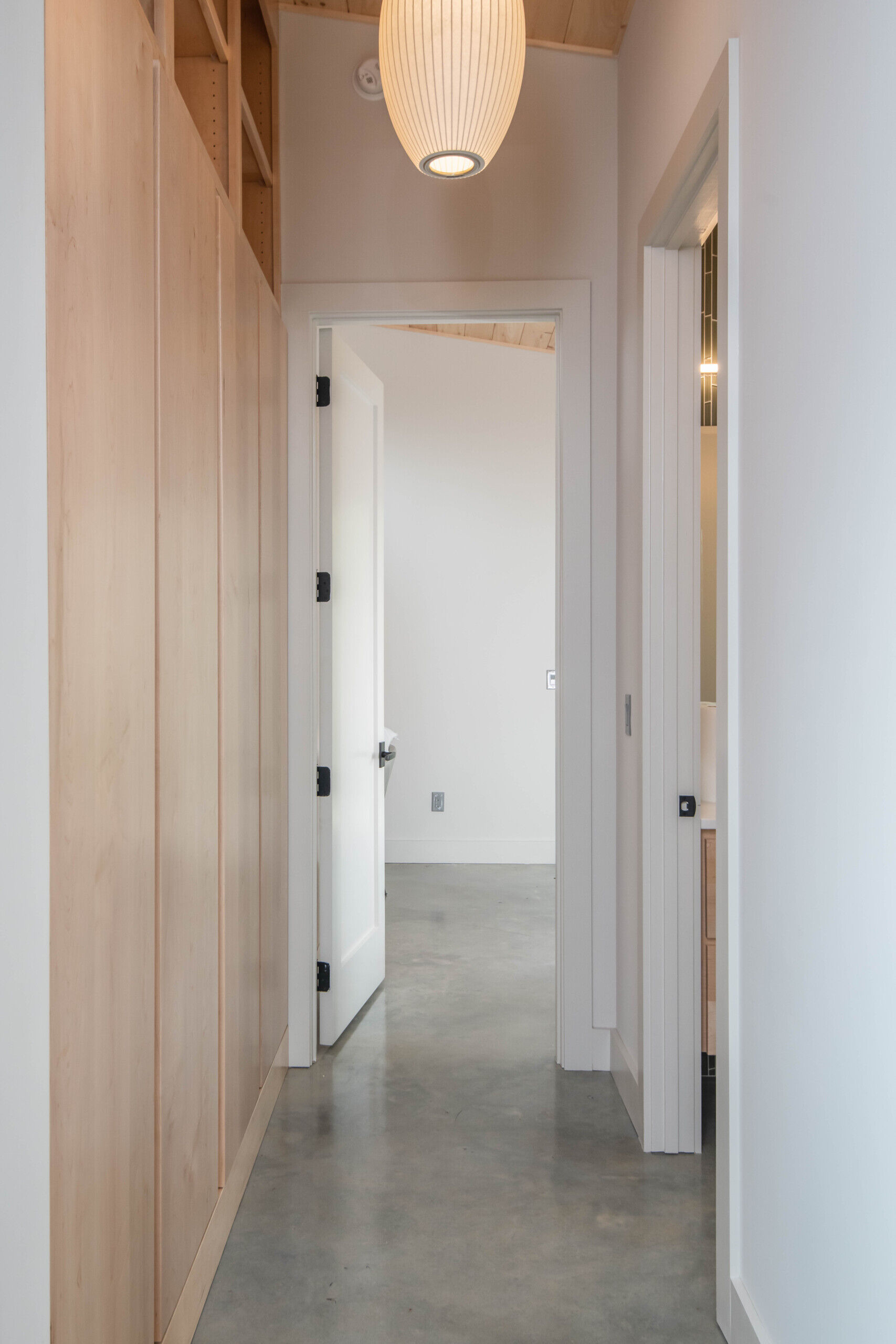 Streamlined hallway with polished concrete floors connecting communal and private areas in a mountain cabin.