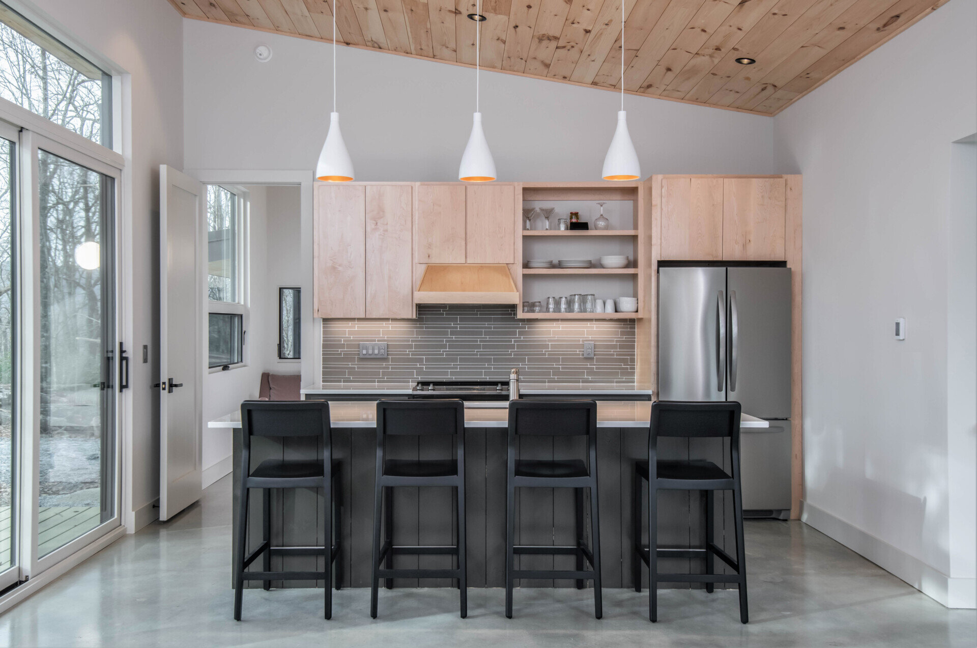 The kitchen mirrors the cabin’s pared-down aesthetic, featuring maple plywood cabinetry and built-ins. Its layout prioritizes simplicity and function, allowing the family to cook, gather, and enjoy meals with the surrounding landscape always in view.