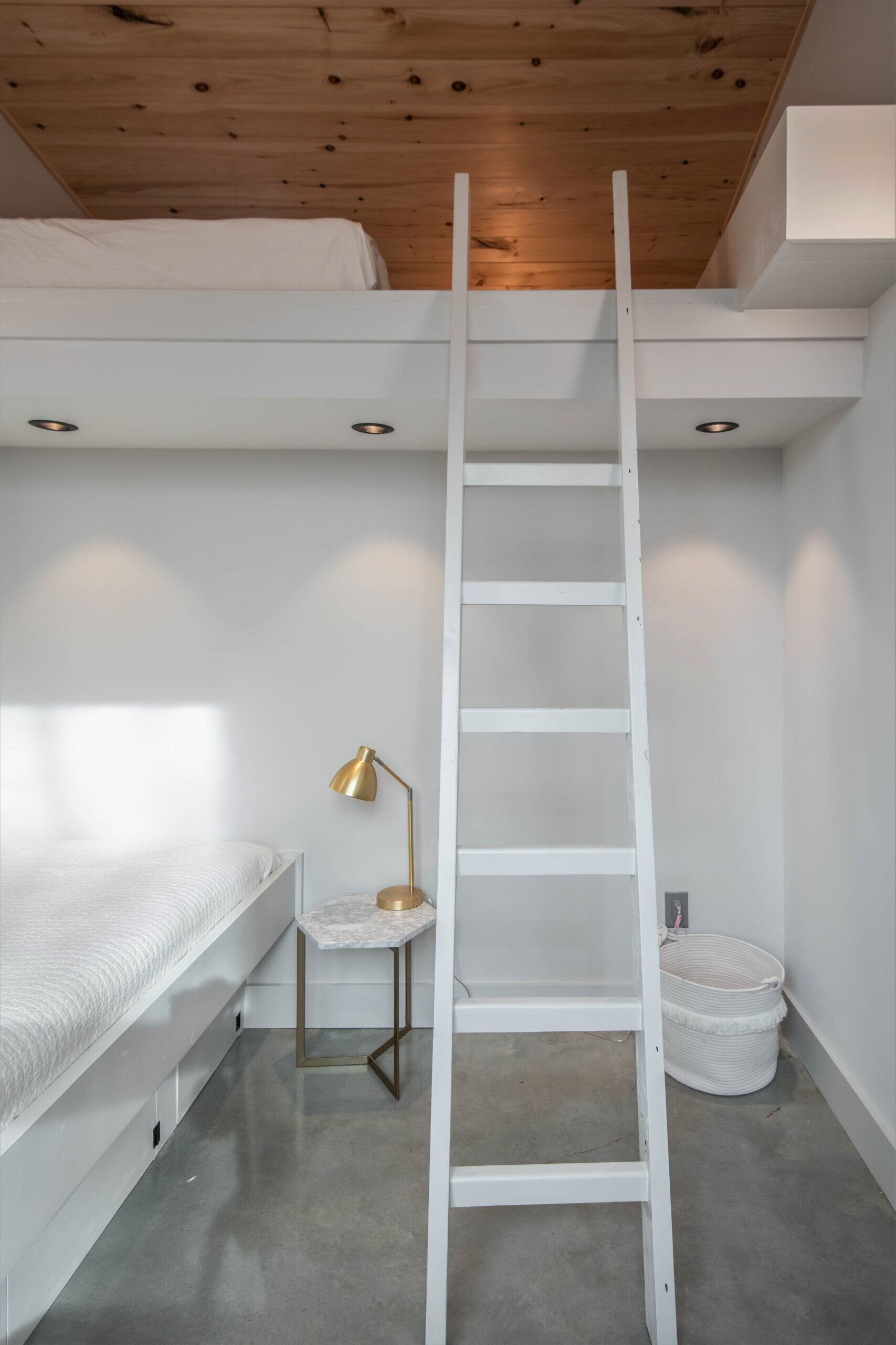 Loft bedroom in a mountain cabin, maximizing space and light while maintaining minimalist, family-friendly design.