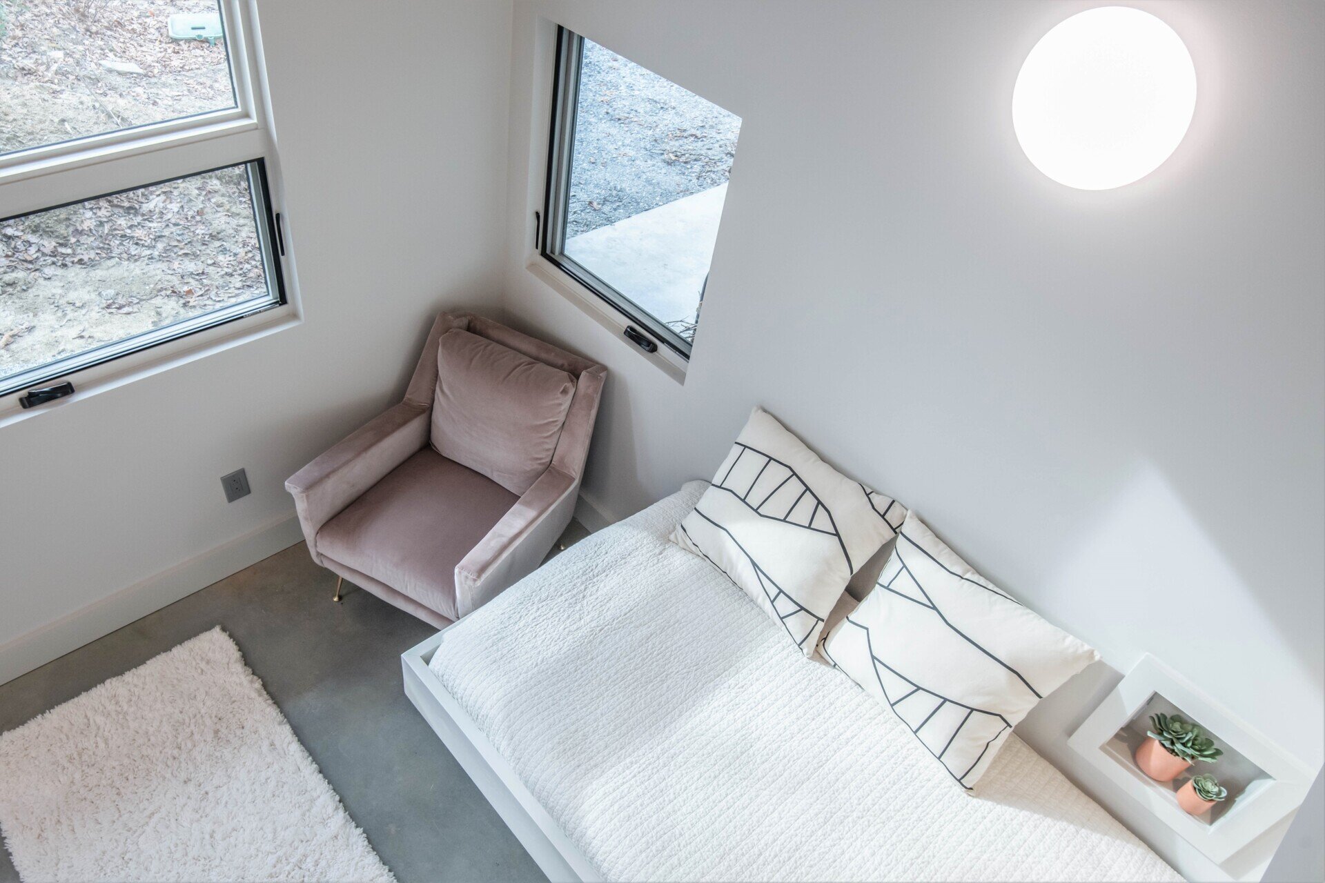 Loft bedroom in a mountain cabin, maximizing space and light while maintaining minimalist, family-friendly design.