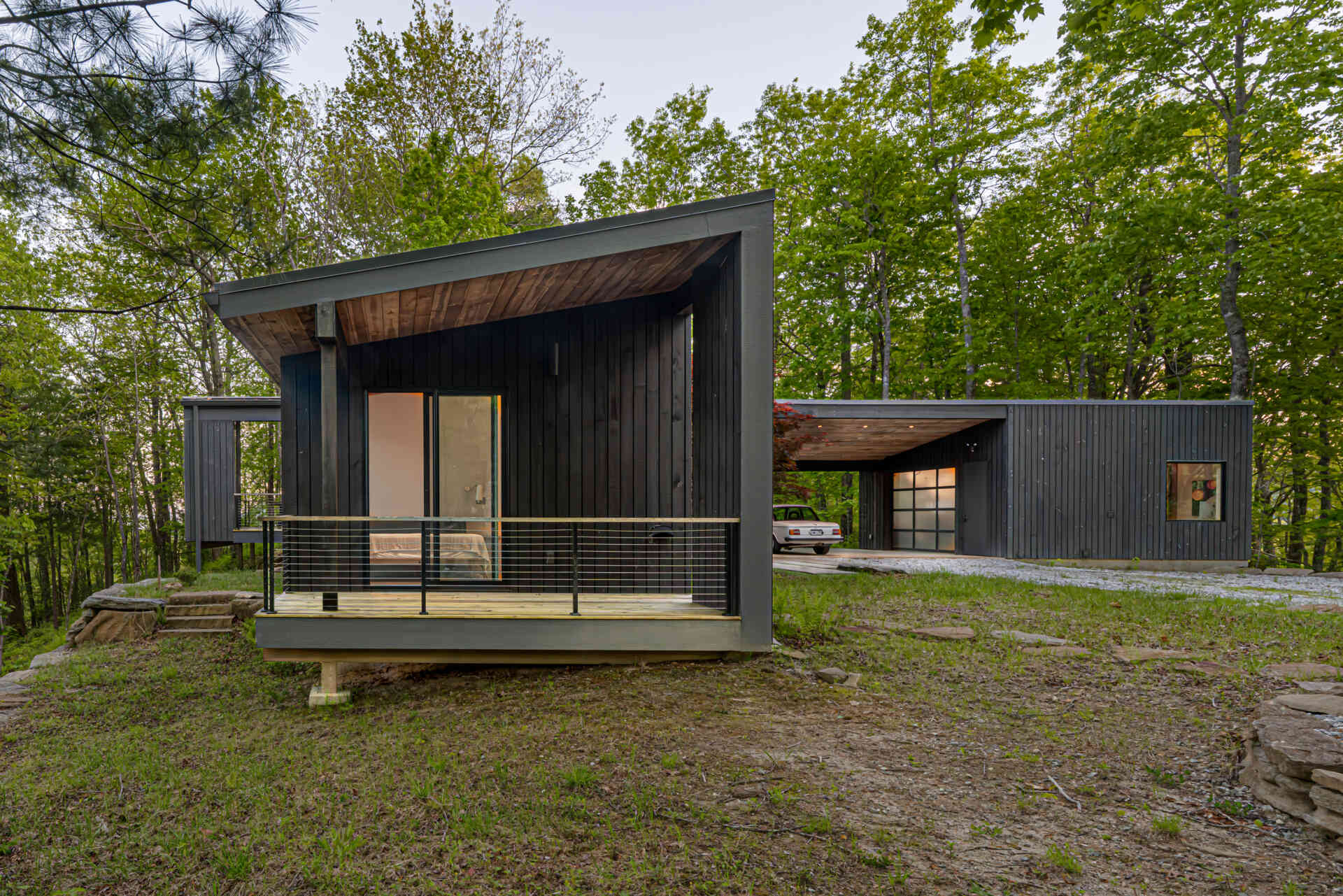 A modern mountain cabin in Sapphire, NC, featuring two pavilions forming a courtyard, black-stained pine exterior, and a minimalist Japanese-Scandinavian design.