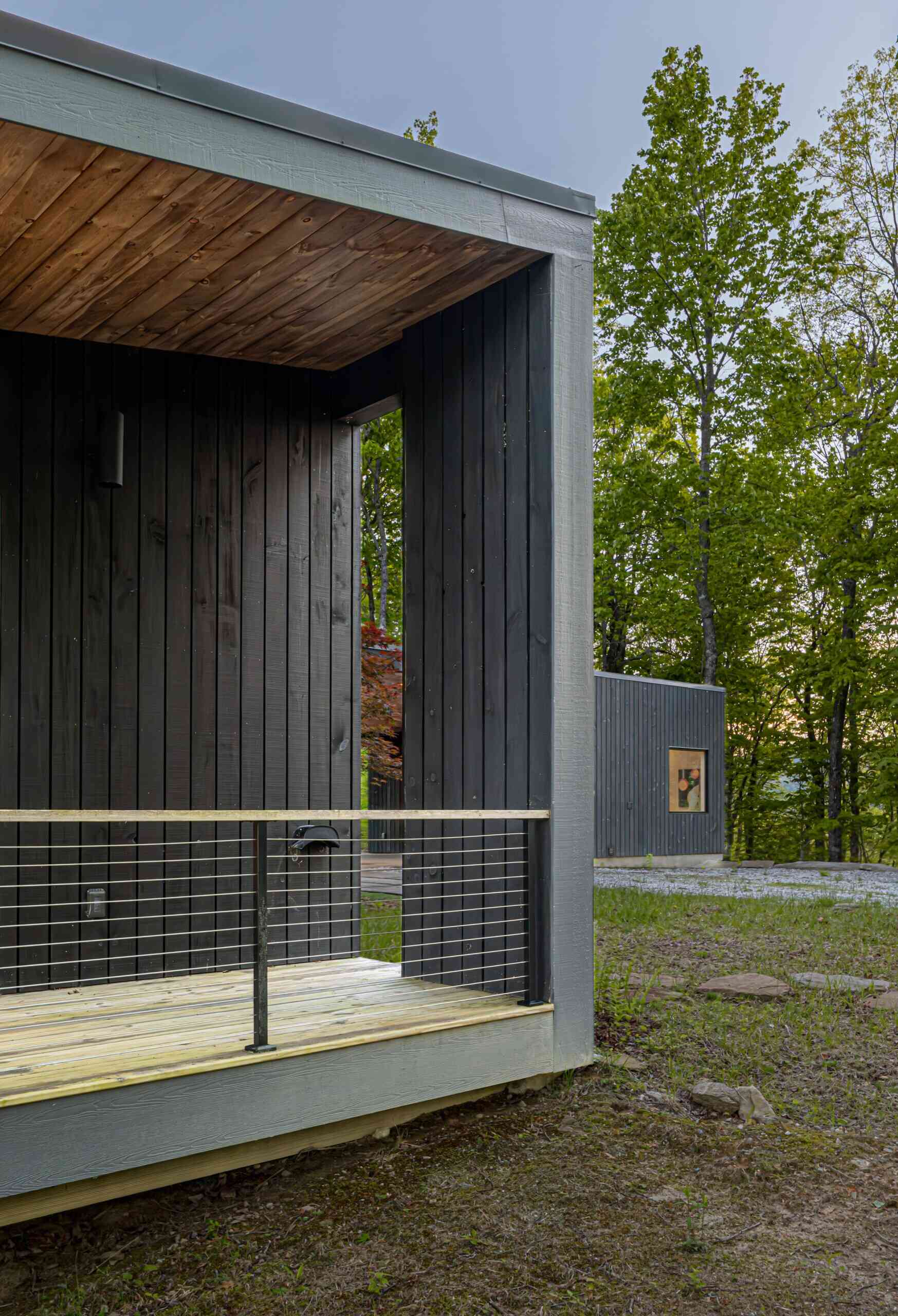 A modern mountain cabin in Sapphire, NC, featuring two pavilions forming a courtyard, black-stained pine exterior, and a minimalist Japanese-Scandinavian design.