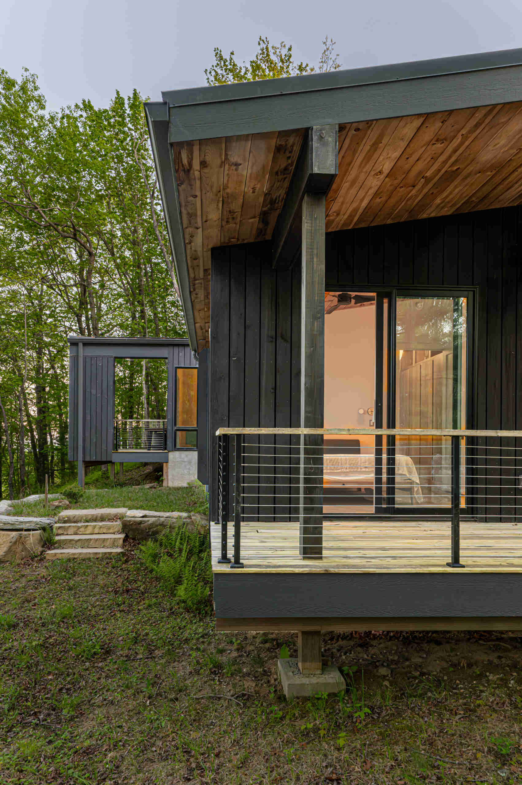 A modern mountain cabin in Sapphire, NC, featuring two pavilions forming a courtyard, black-stained pine exterior, and a minimalist Japanese-Scandinavian design.