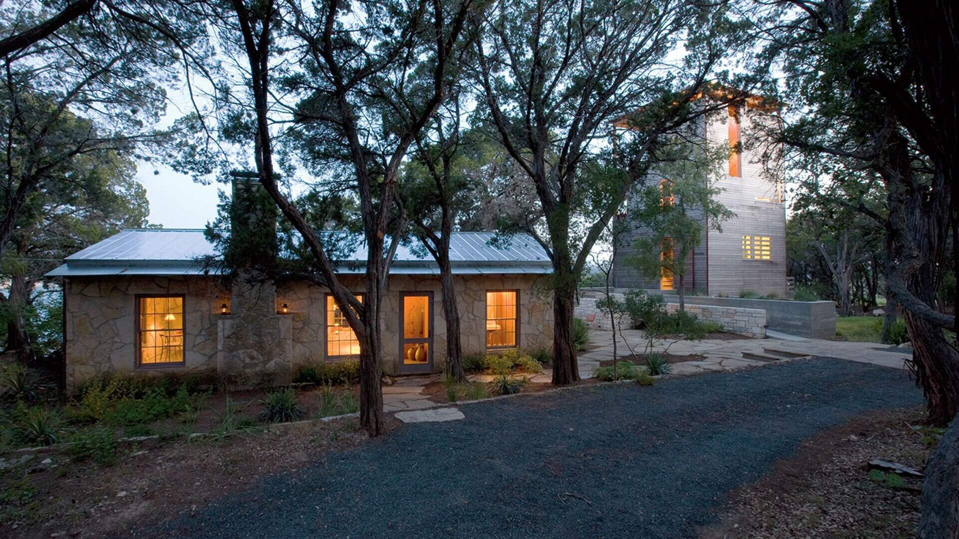A modern tower built beside a 1930s cabin in Austin, Texas, blending old stone and new wood in a serene forest retreat.