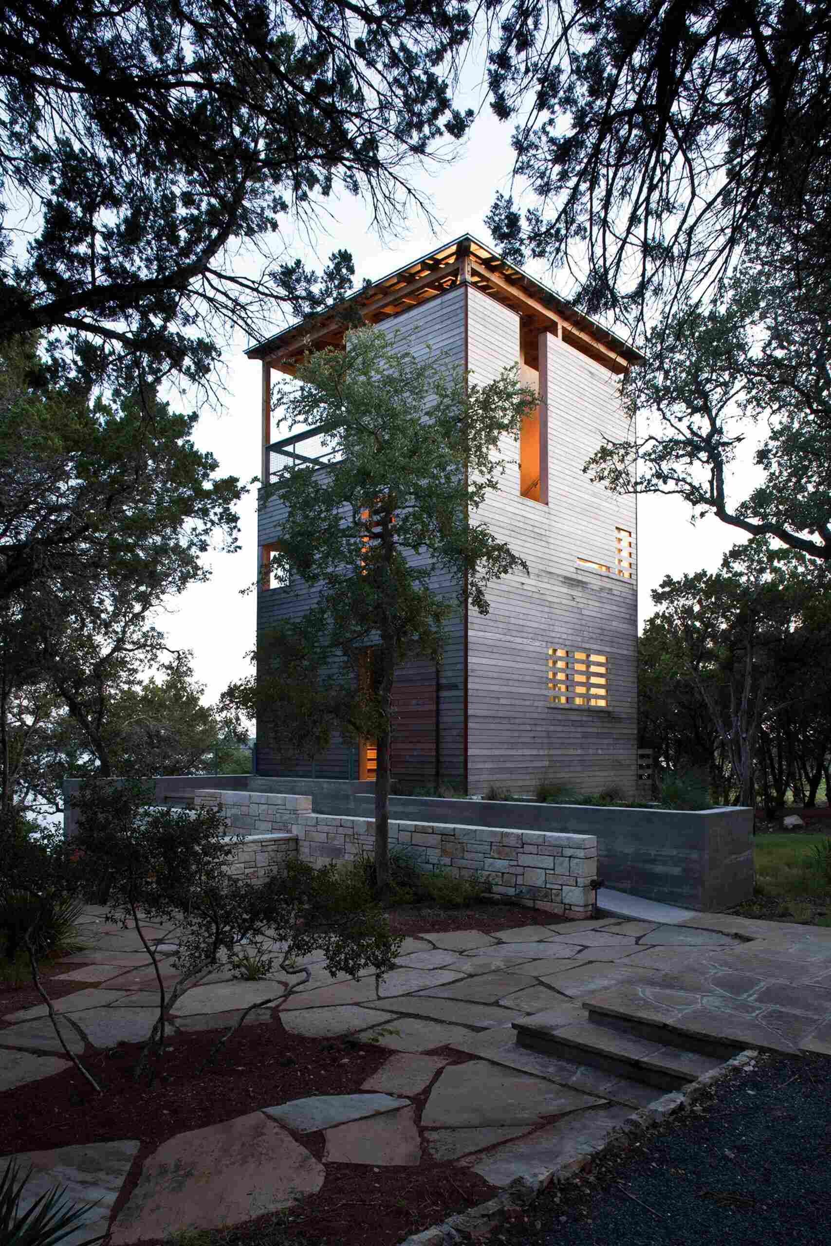 A modern tower built beside a 1930s cabin in Austin, Texas, blending old stone and new wood in a serene forest retreat.