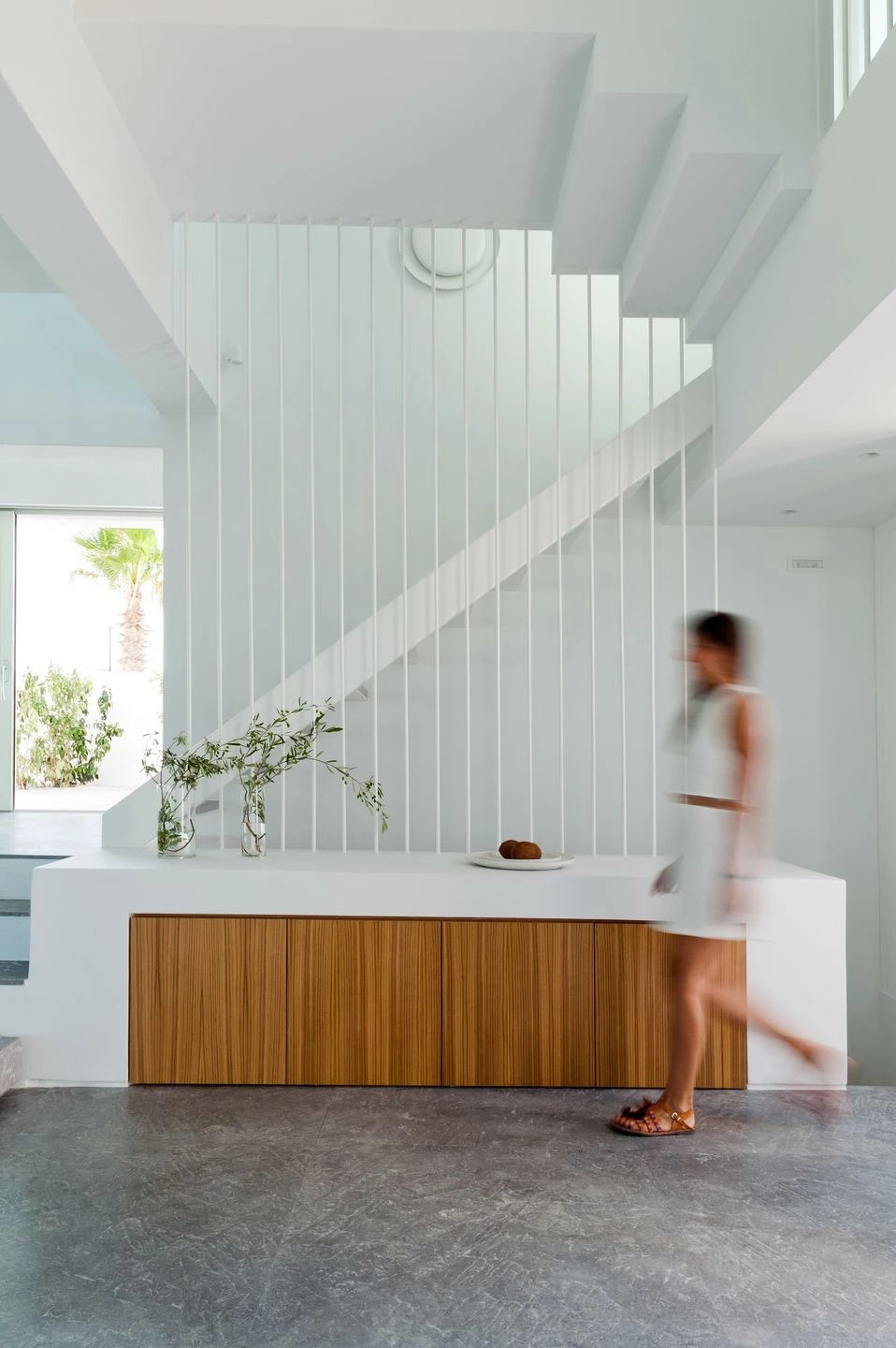 White cabinets blend into the walls, while Gortynis grey marble adds quiet sophistication to the stairs and hallway in this minimalist Greek home.