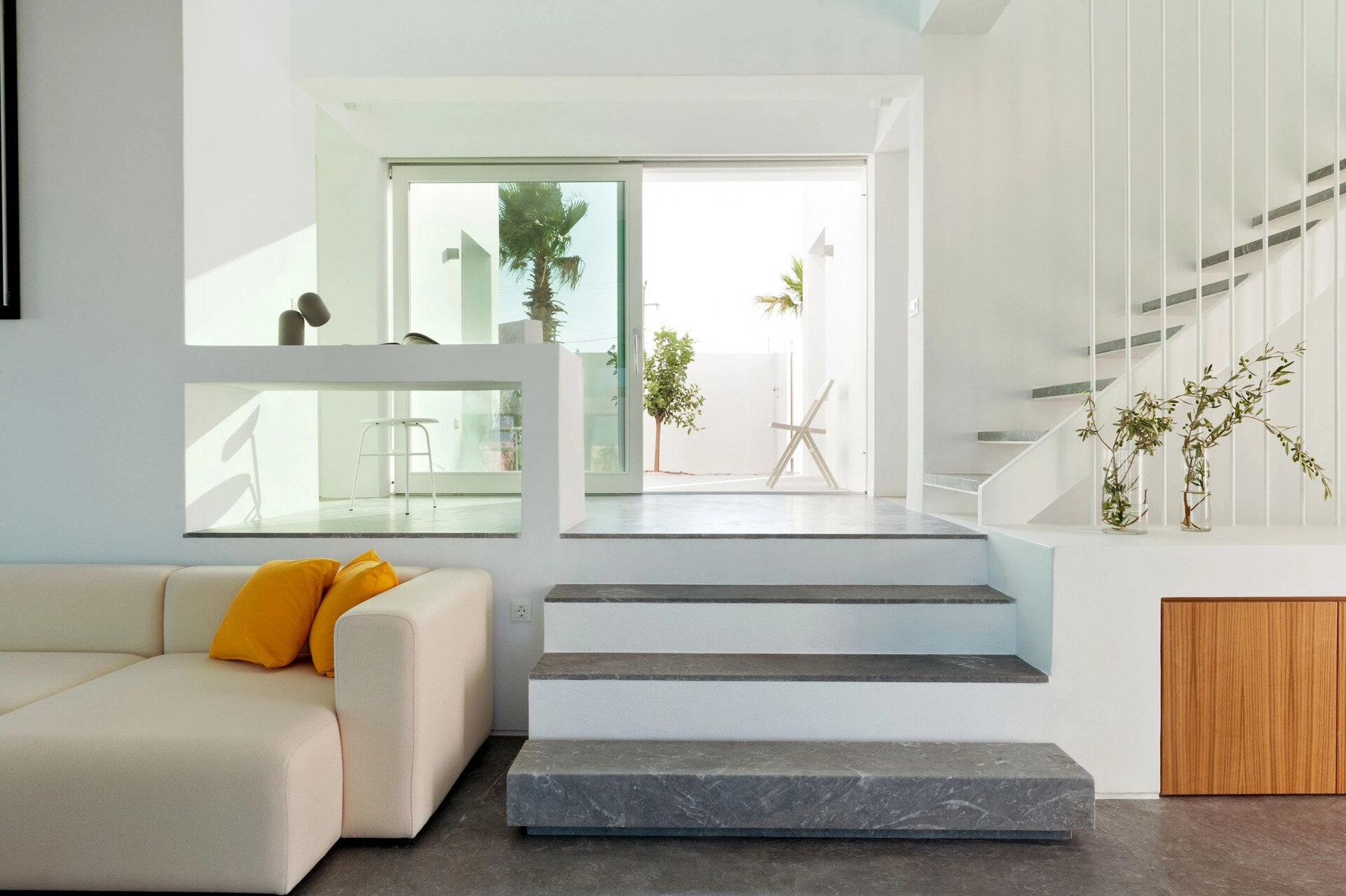White cabinets blend into the walls, while Gortynis grey marble adds quiet sophistication to the stairs and hallway in this minimalist Greek home.