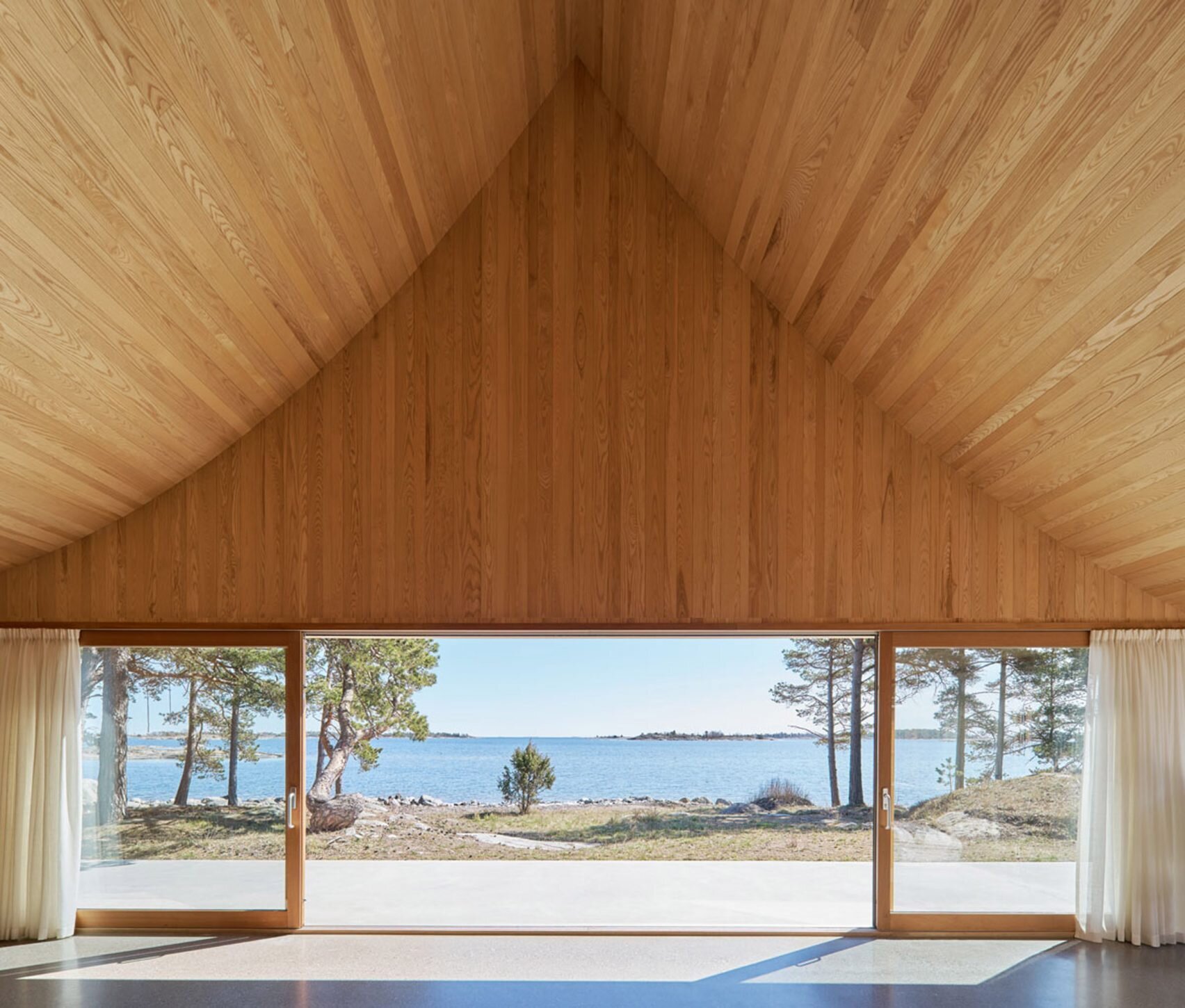 Soaring ceilings and sliding glass doors make this cedar-lined living room feel like an open-air pavilion, blurring the line between home and nature.