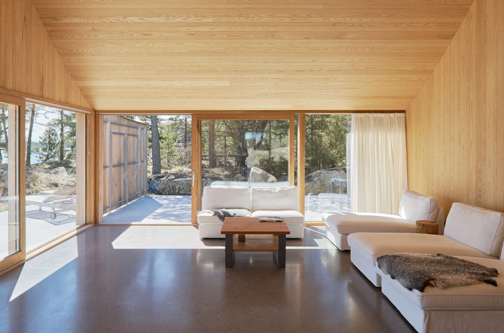 Soaring ceilings and sliding glass doors make this cedar-lined living room feel like an open-air pavilion, blurring the line between home and nature.