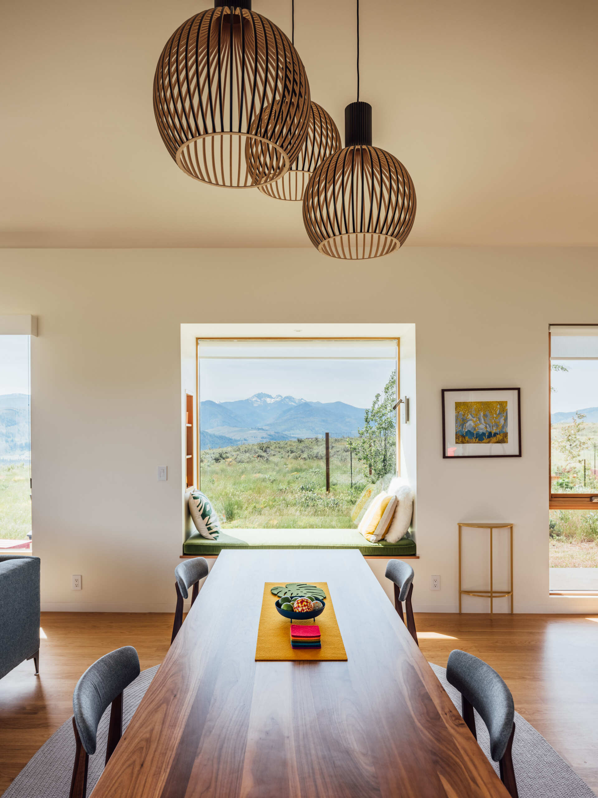 A solid wood table and understated pendant lighting define the dining area’s quiet elegance. With the window seat nearby, every meal unfolds against a backdrop of mountain light and calm design.