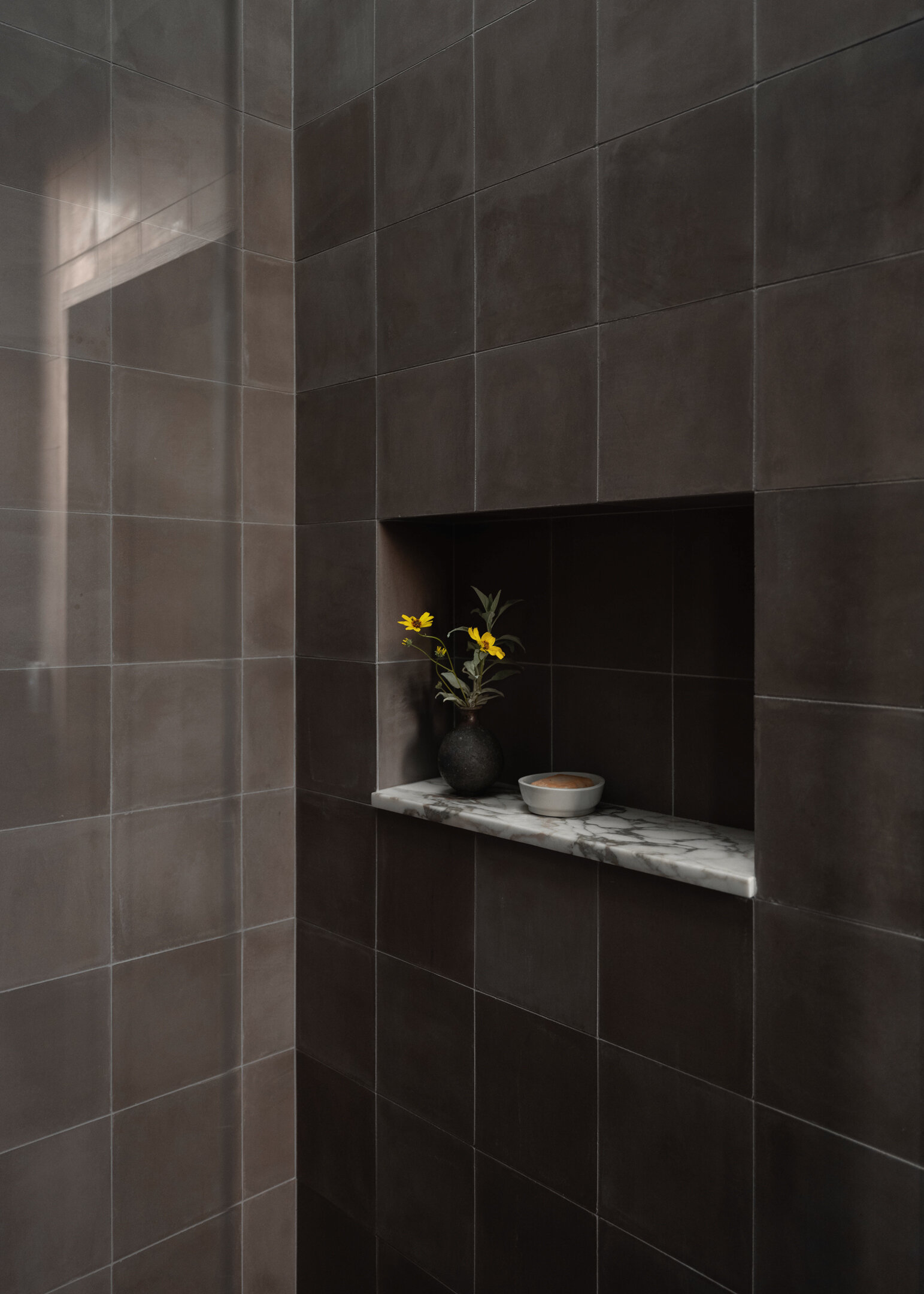 Natural stone, wood, and handmade tile come together in a small yet refined bathroom designed around light, texture, and simplicity.